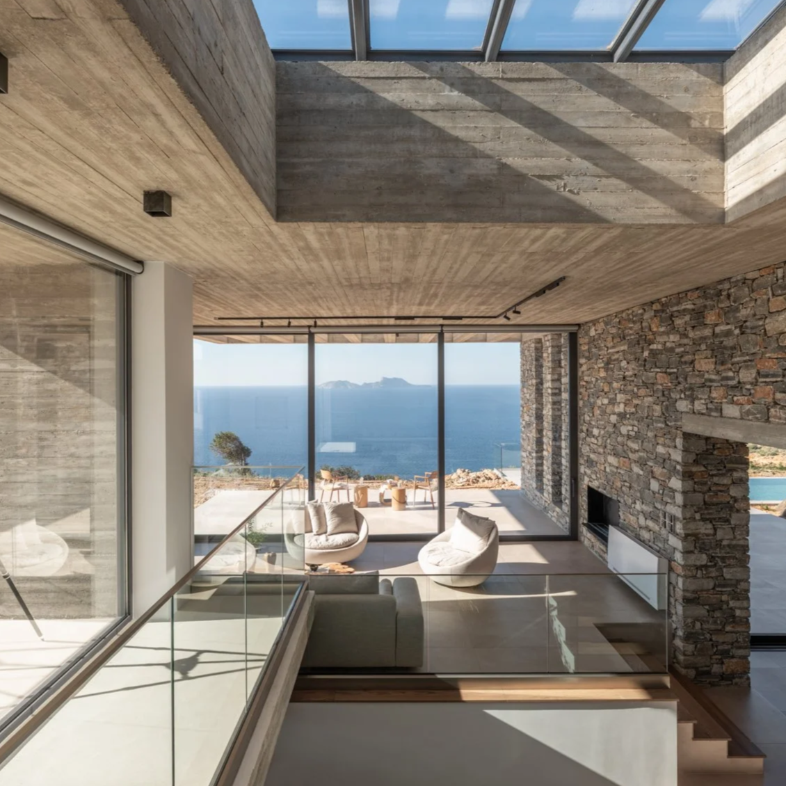 Interior of Keras Cliff House in South Crete with open-plan living space framing panoramic sea views through floor-to-ceiling windows.