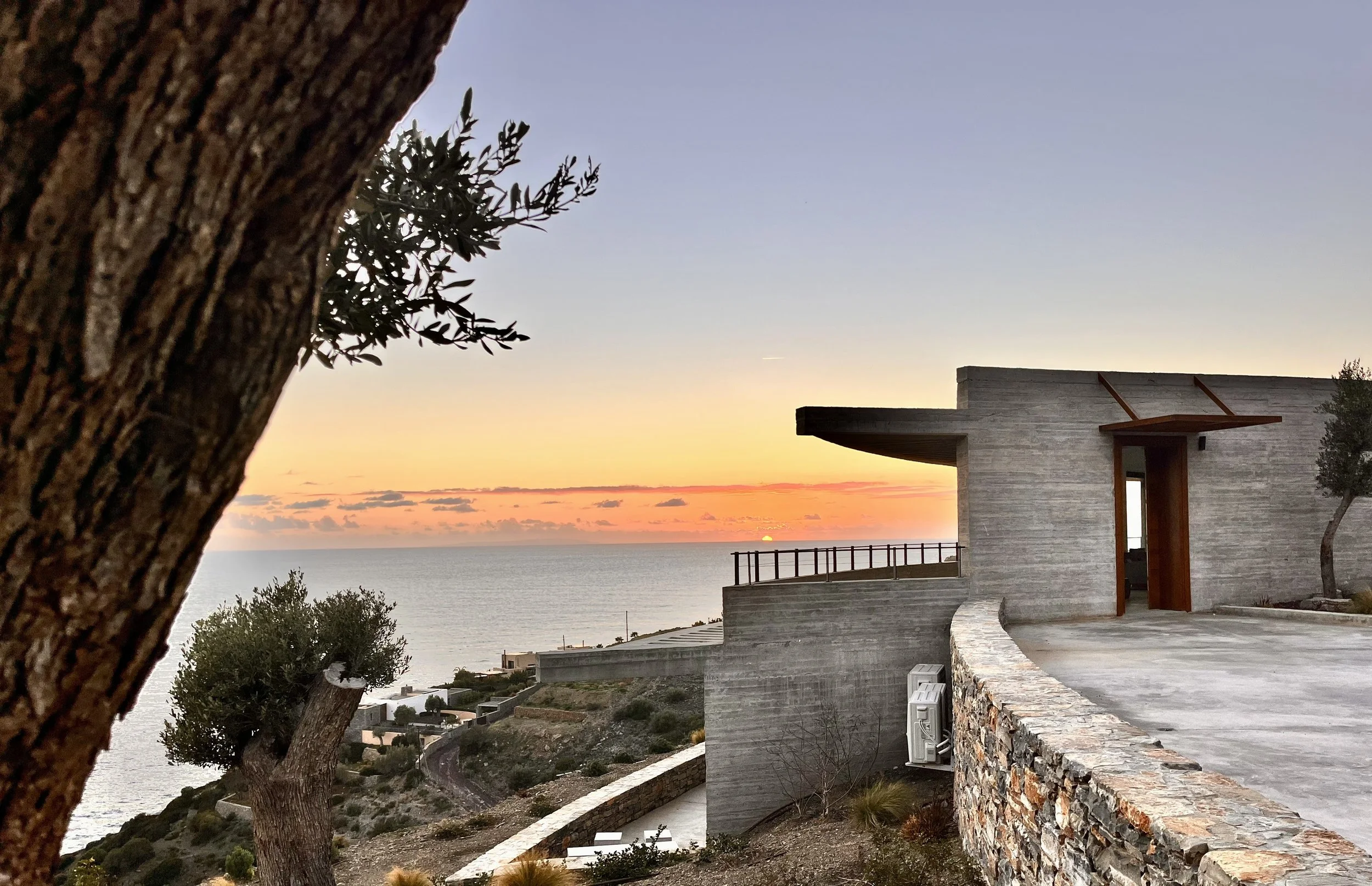 Sunset behind Villa Eulimene and the Libyan Sea in South Crete with olive tree trunk in the foreground.
