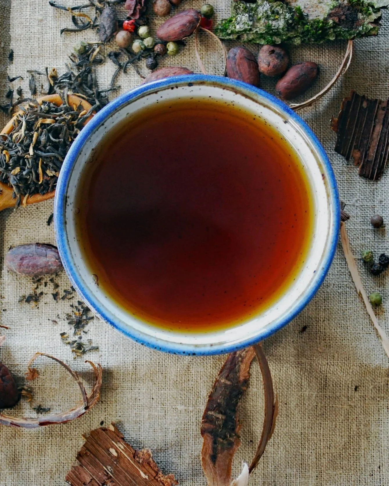 Cup of Cretan tea on a linen cloth covered with herbs and seeds