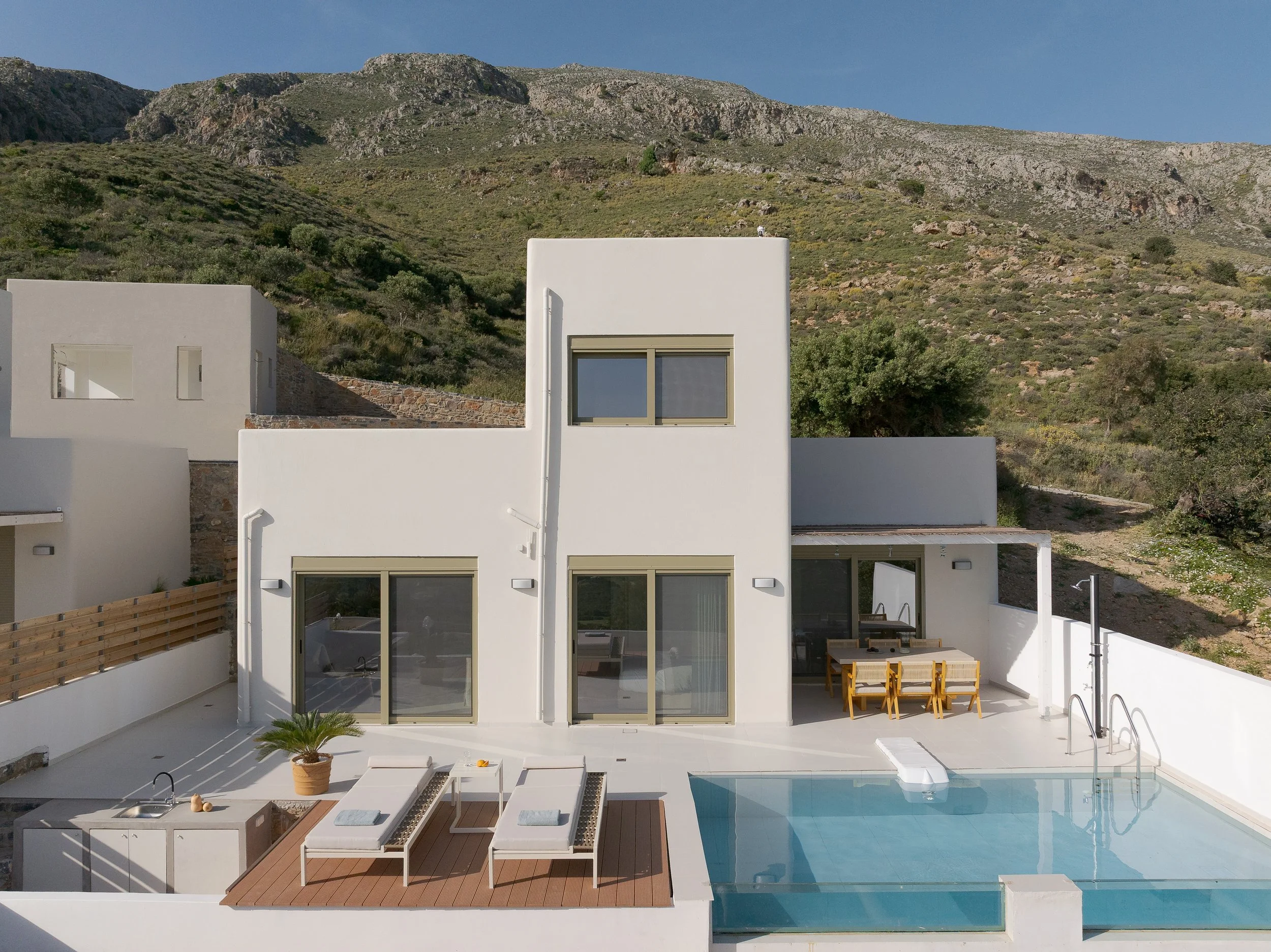 Aitherion villa in South Crete near Plakias with sun loungers and open views across the landscape under a bright, expansive sky.