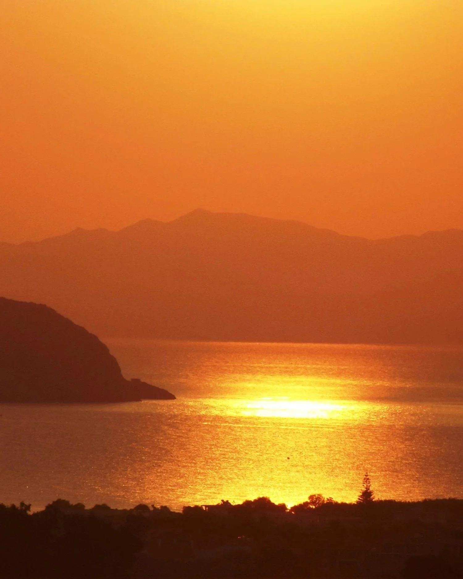 Sunset paints the sky orange over the mountains of South Crete and the Libyan Sea