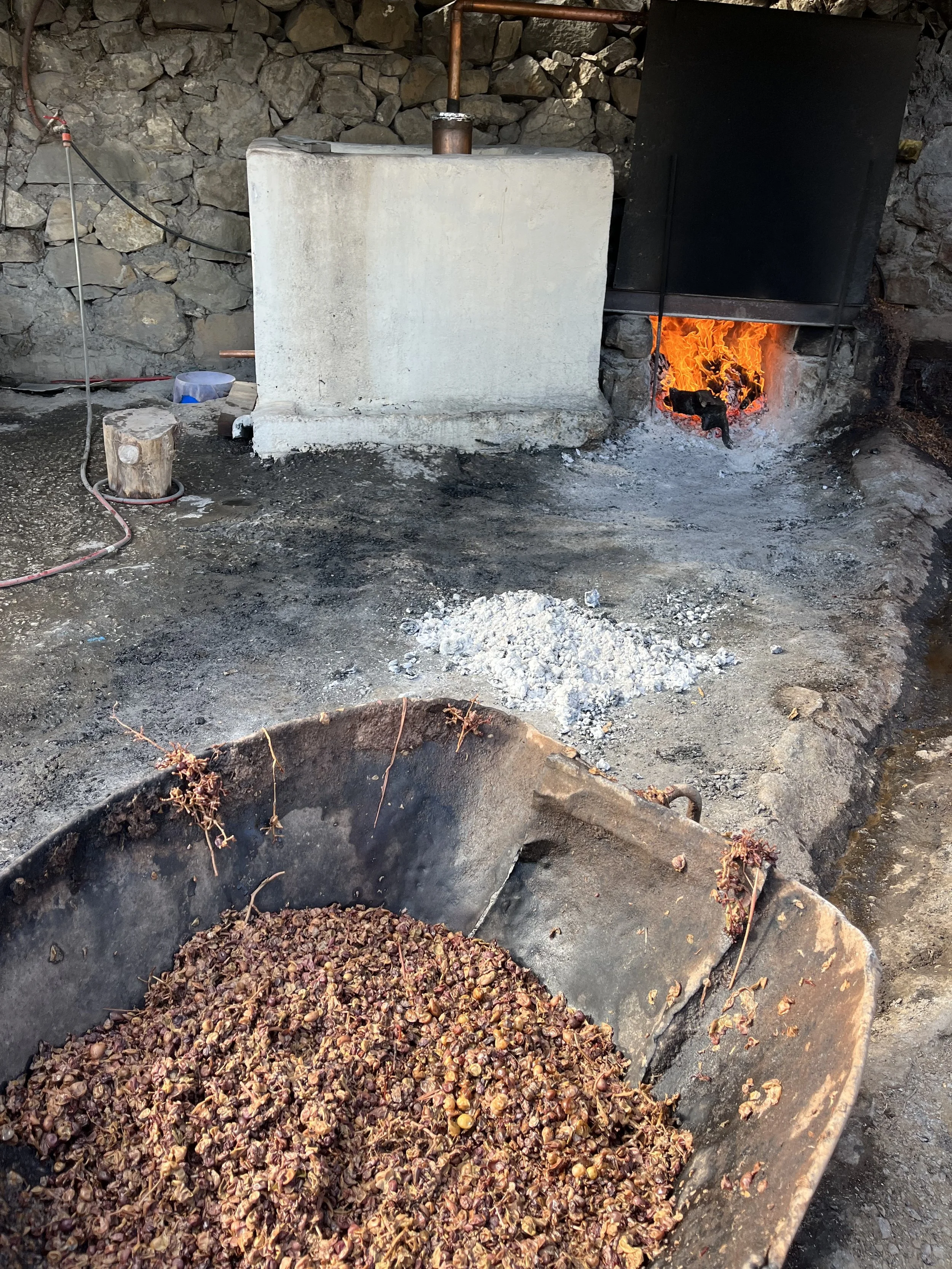 Grape pomace in a cart in front of a village raki distillery with burning fire in South Crete.