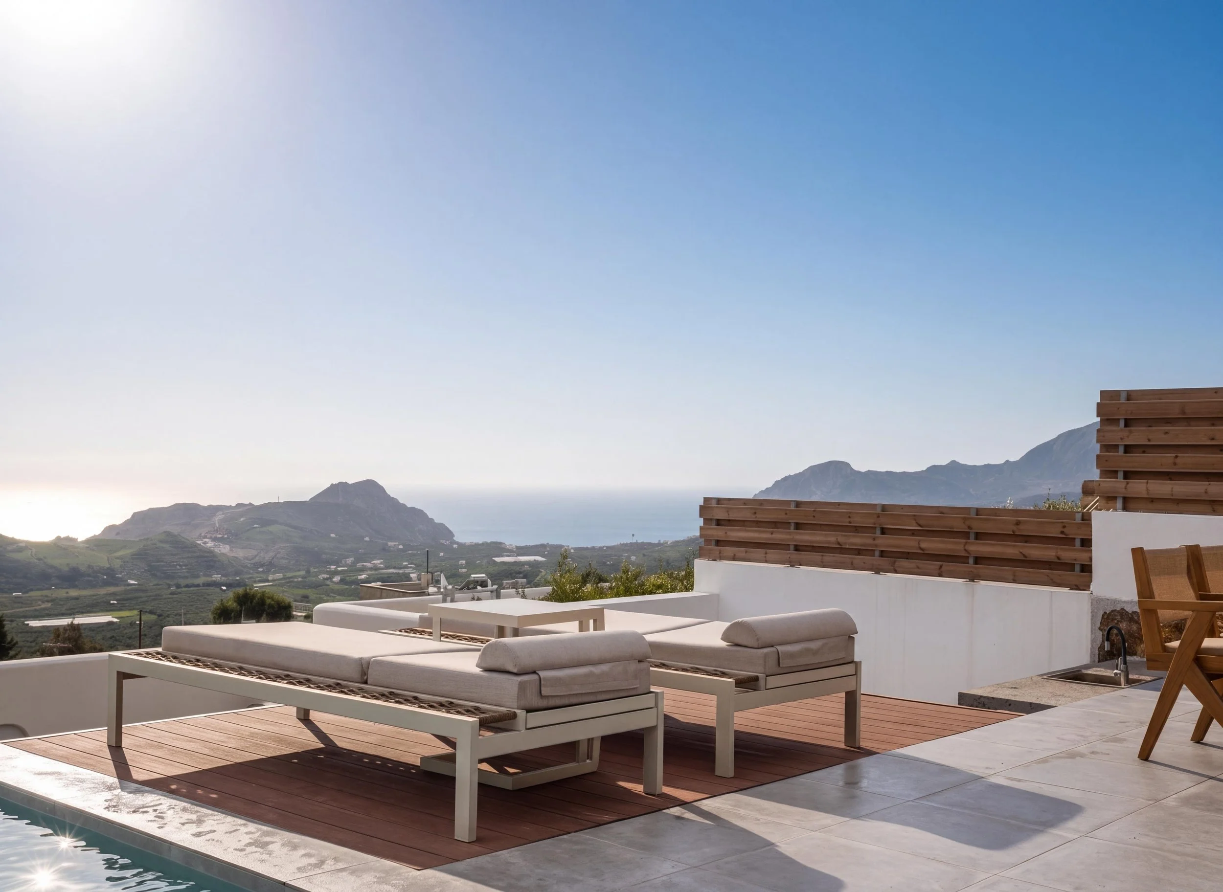 Aitherion villa terrace in South Crete near Plakias with sun loungers and open views across the landscape under a bright, expansive sky.