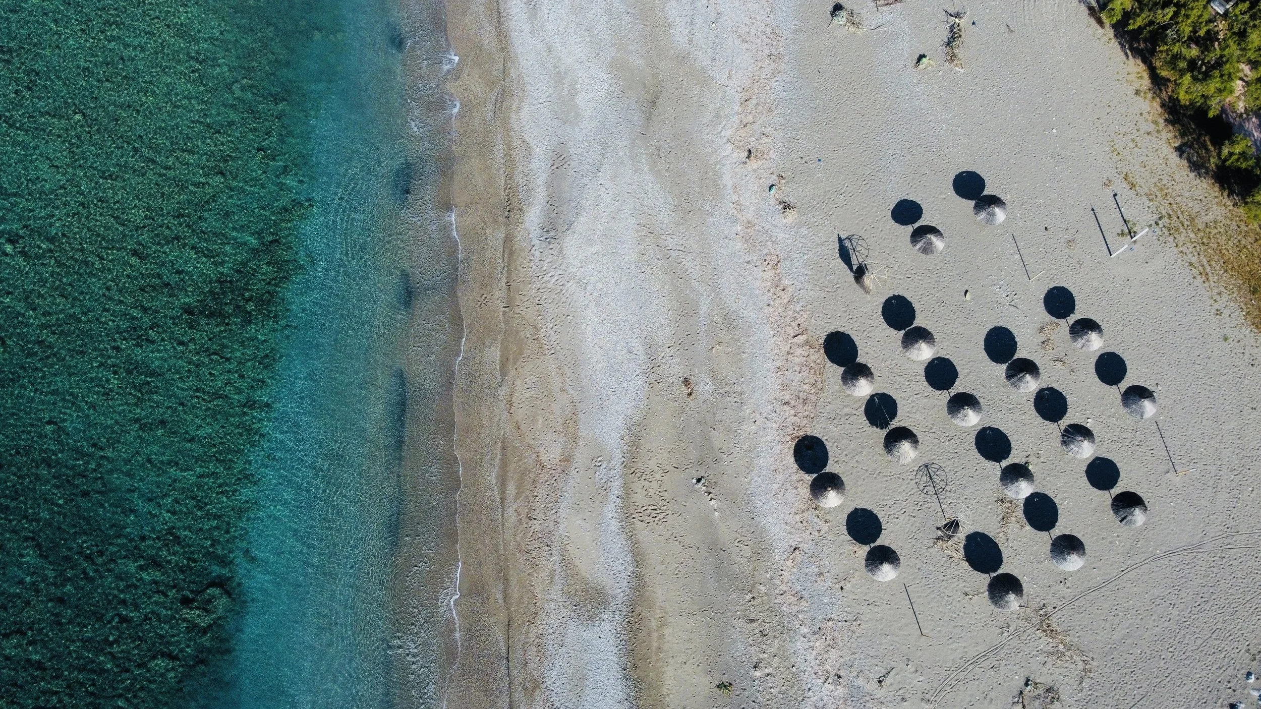 Bird's eye view of beach at Kokkinos Pirgos, South Crete, with turquoise water and umbrellas.