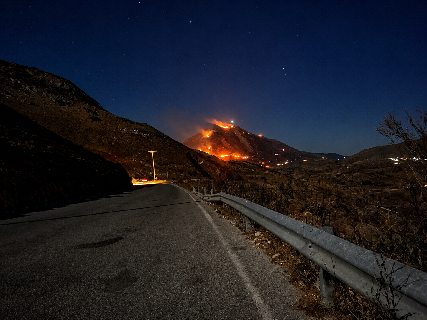 Wildfire burning on a mountain near Akoumia at night, viewed from a mountain road in South Crete.