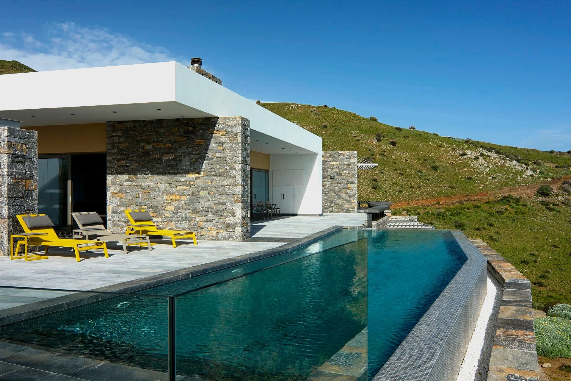 Villa Faros in Agios Pavlos with private infinity pool, modern stone architecture, and panoramix hillside views overlooking the Libyan Sea.