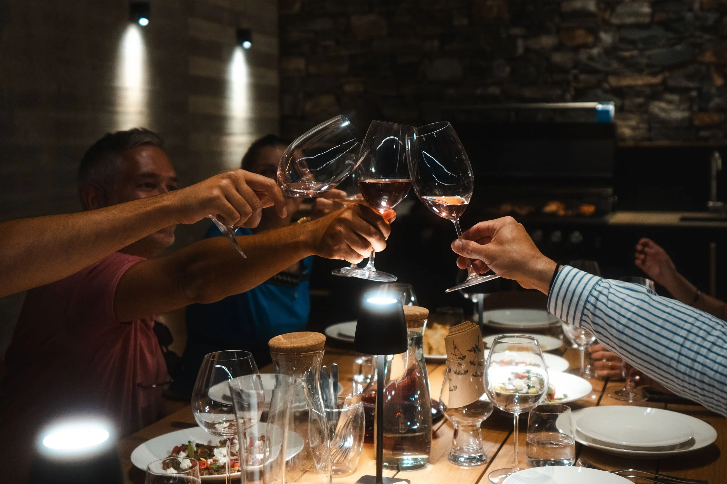 Group of friends toasting with wine glasses during private chef dinner during villa holidays in Crete