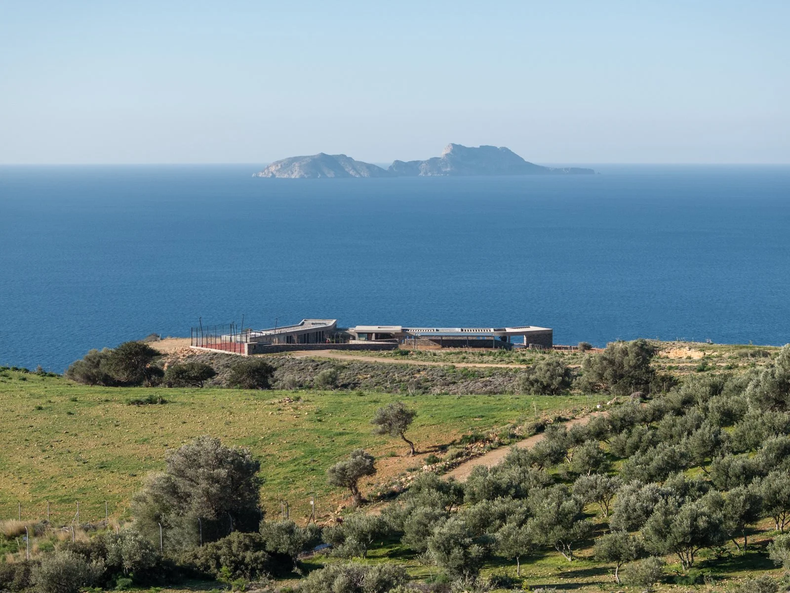 View of luxury villa Keras Cliff House in South Crete with olive grove, view of the Libyan Sea and Paximadia Islands on the horizon.