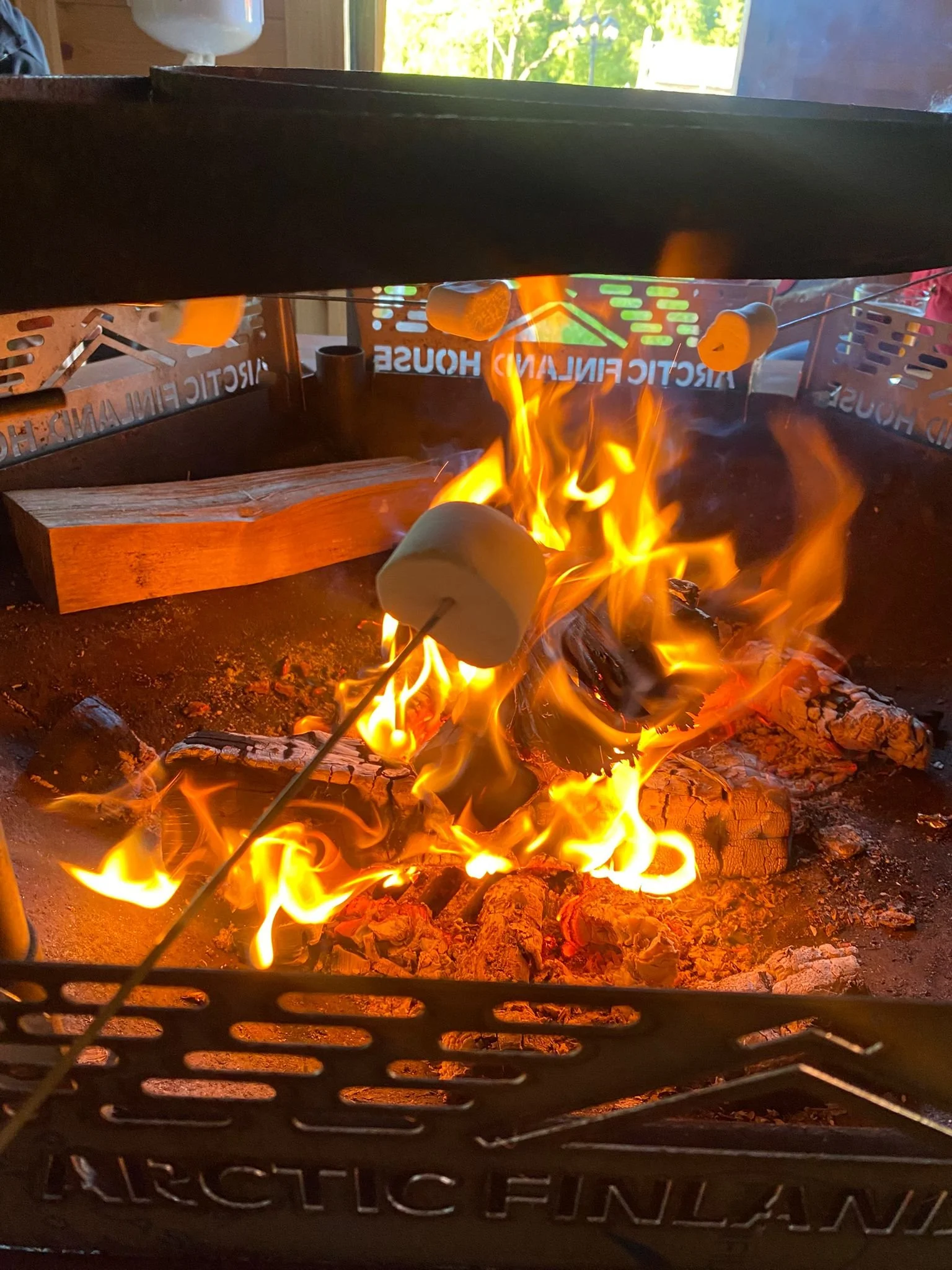 Marshmallow wird über einem Feuer in einem Holzgrill geröstet.