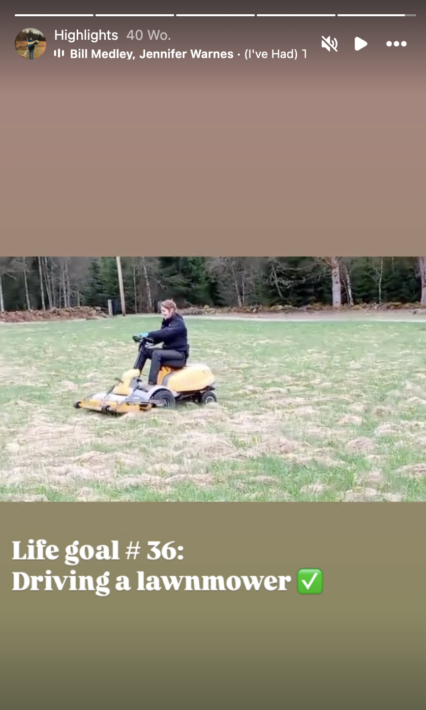 Person fährt mit einem Rasenmäher über ein Feld