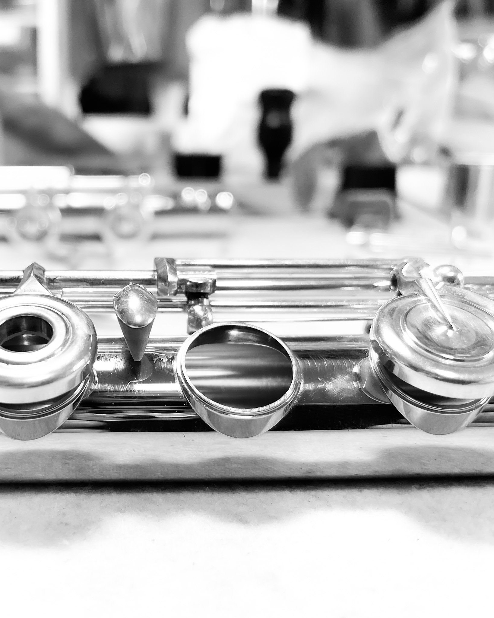 Close-up of shiny keys of a flute on a flat surface, with a blurred background.