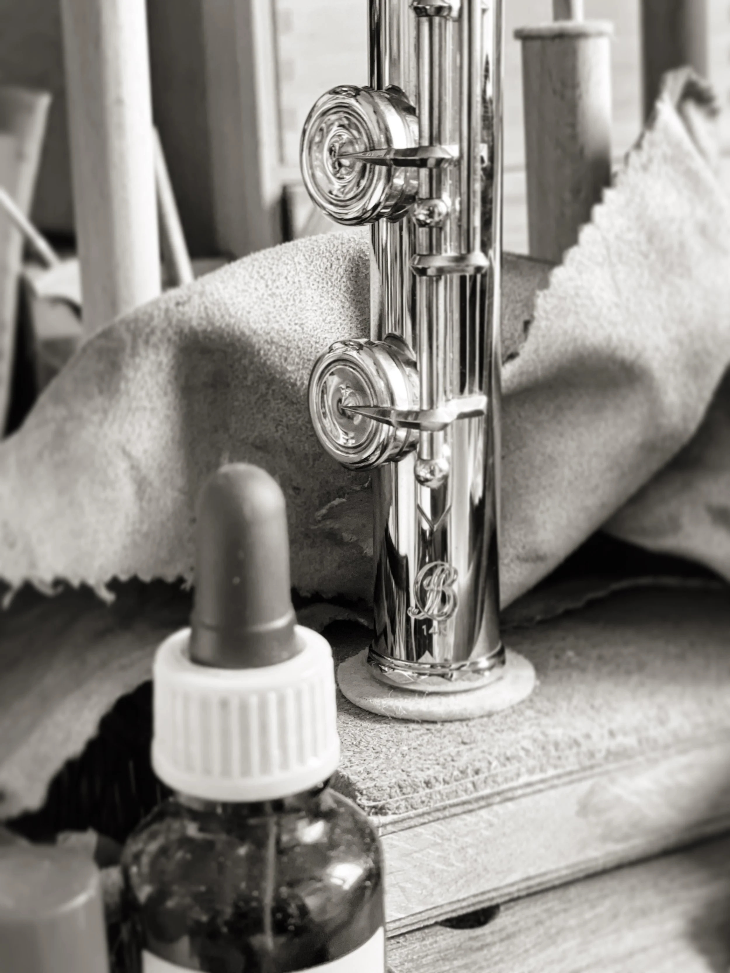 Close-up view of a 14k Brannen Flute footjoint a with logo. The background shows workshop setting with a polishing cloth behind the instrument.