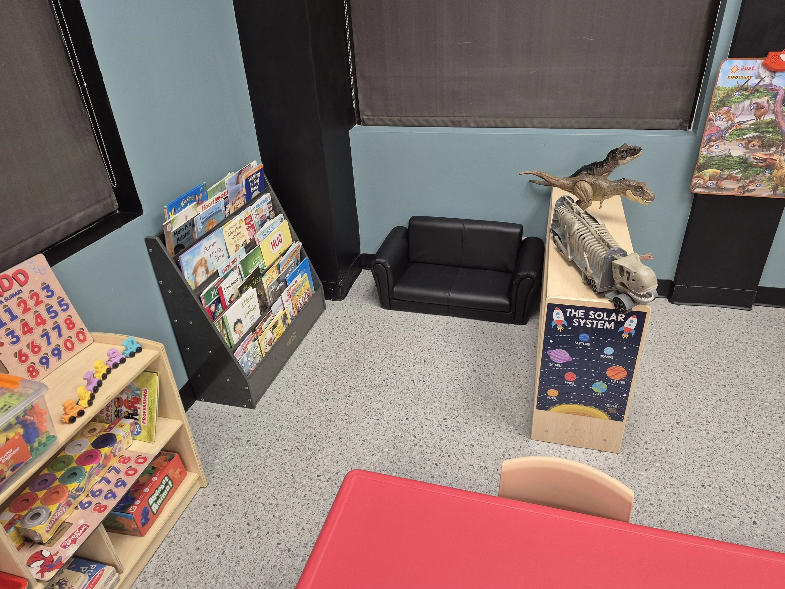 Picture-book displays and a reading corner beside a classroom table.