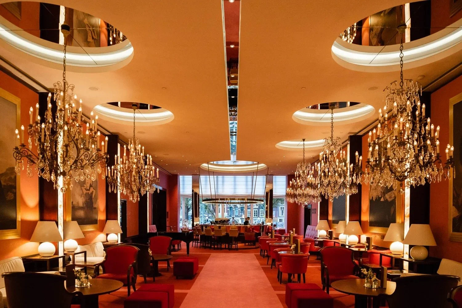 Elegant hotel lounge with crystal chandeliers and red velvet seating set for corporate event reception at luxury Amsterdam venue — event photographer Amsterdam Ballo Studio