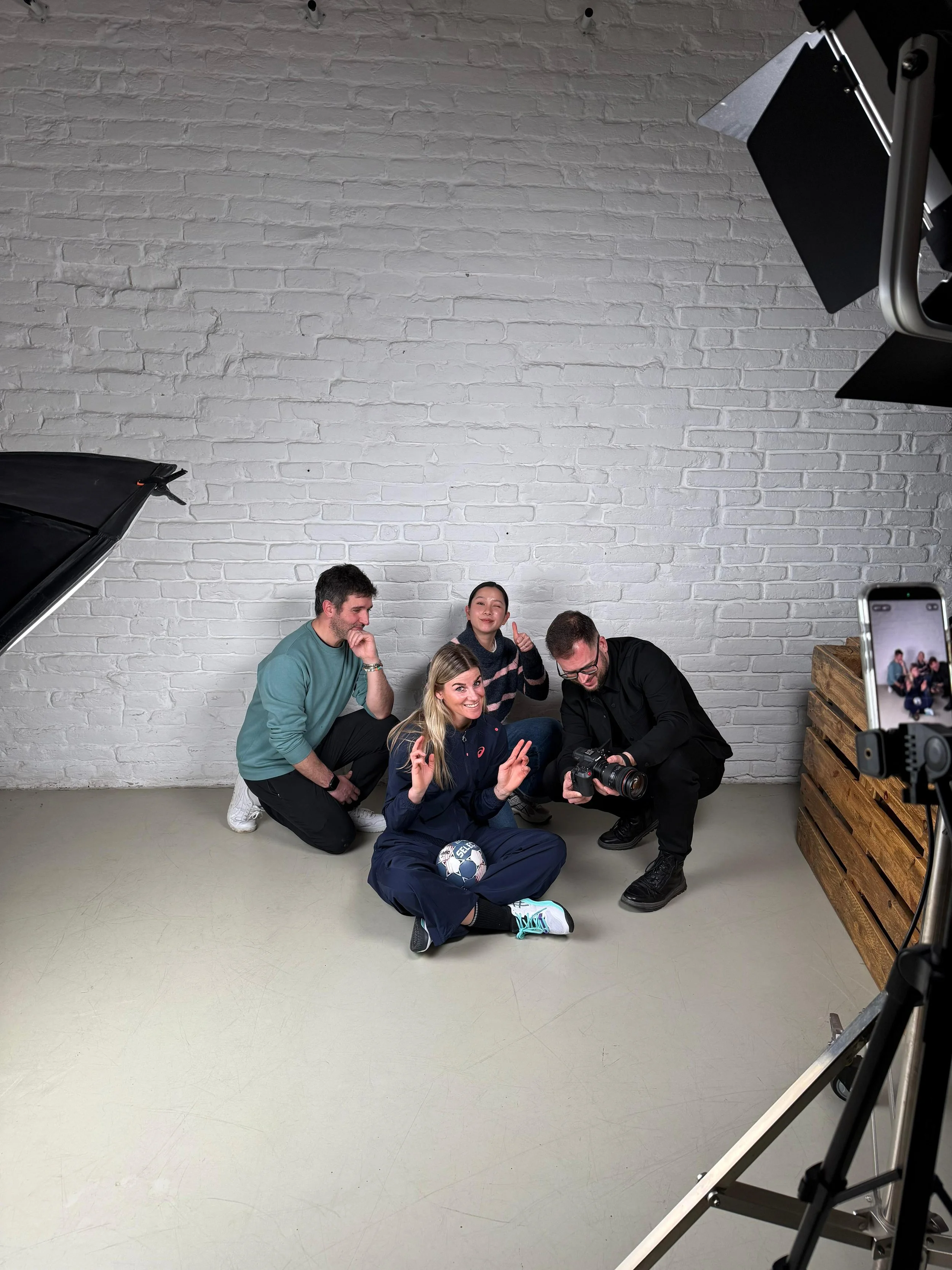 ASICS handball Ballo Studio production crew posing with sponsored athlete holding handball in white brick studio Hungary — sports photography Ballo Studio