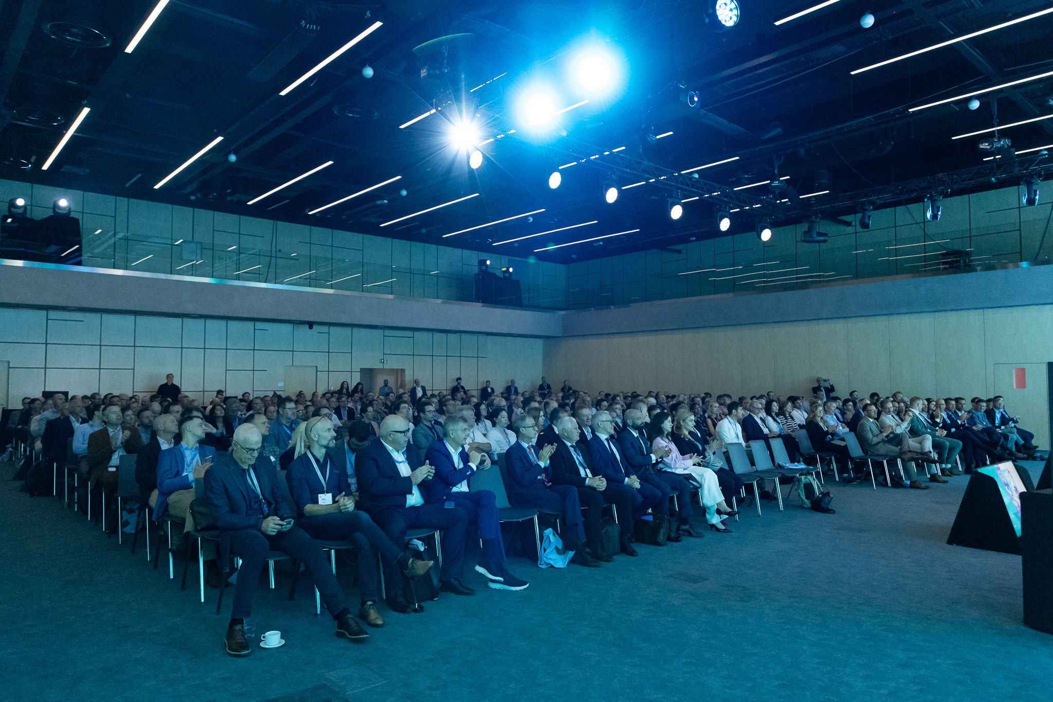 Three panelists on teal-lit stage with audience in foreground at Euroheat & Power Congress Amsterdam — conference photography Ballo Studio