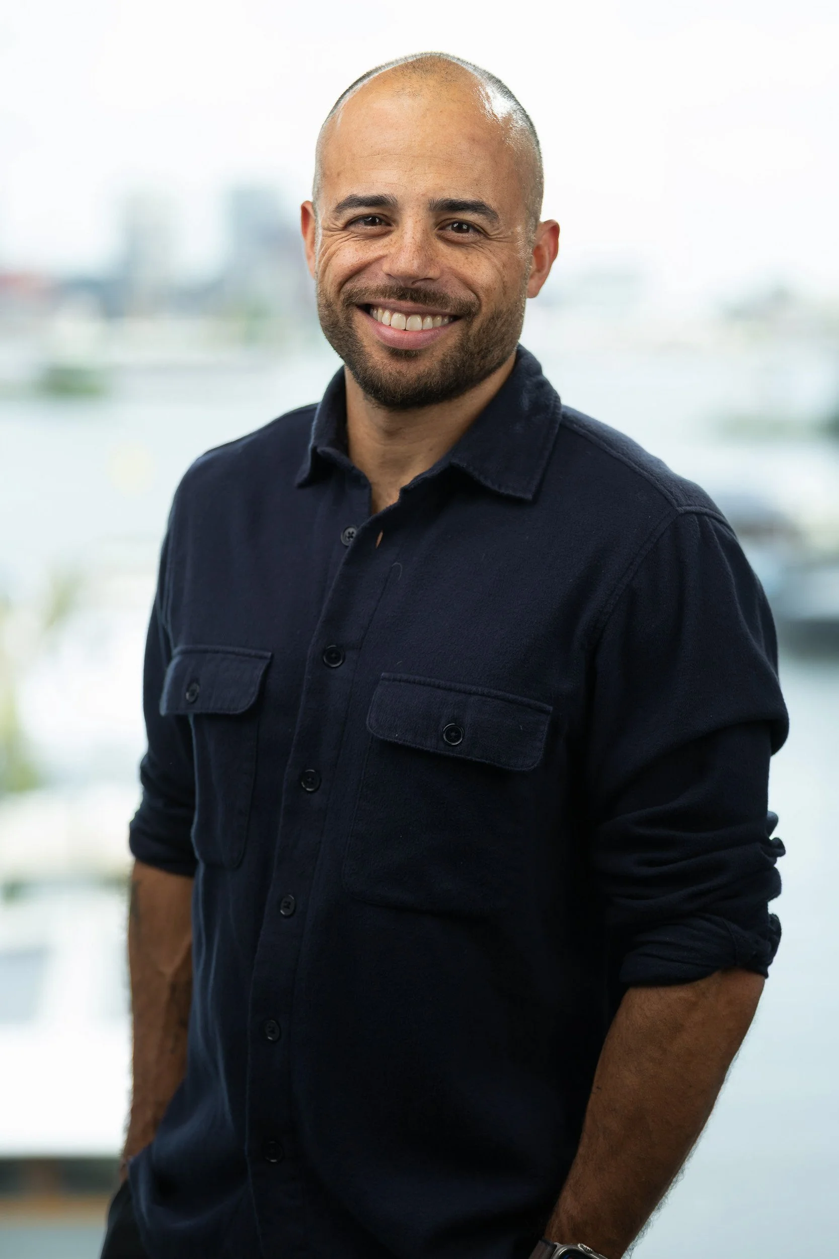 Confident male employee portrait in navy shirt with Amsterdam waterfront background — on-site headshot studio Amsterdam Ballo Studio