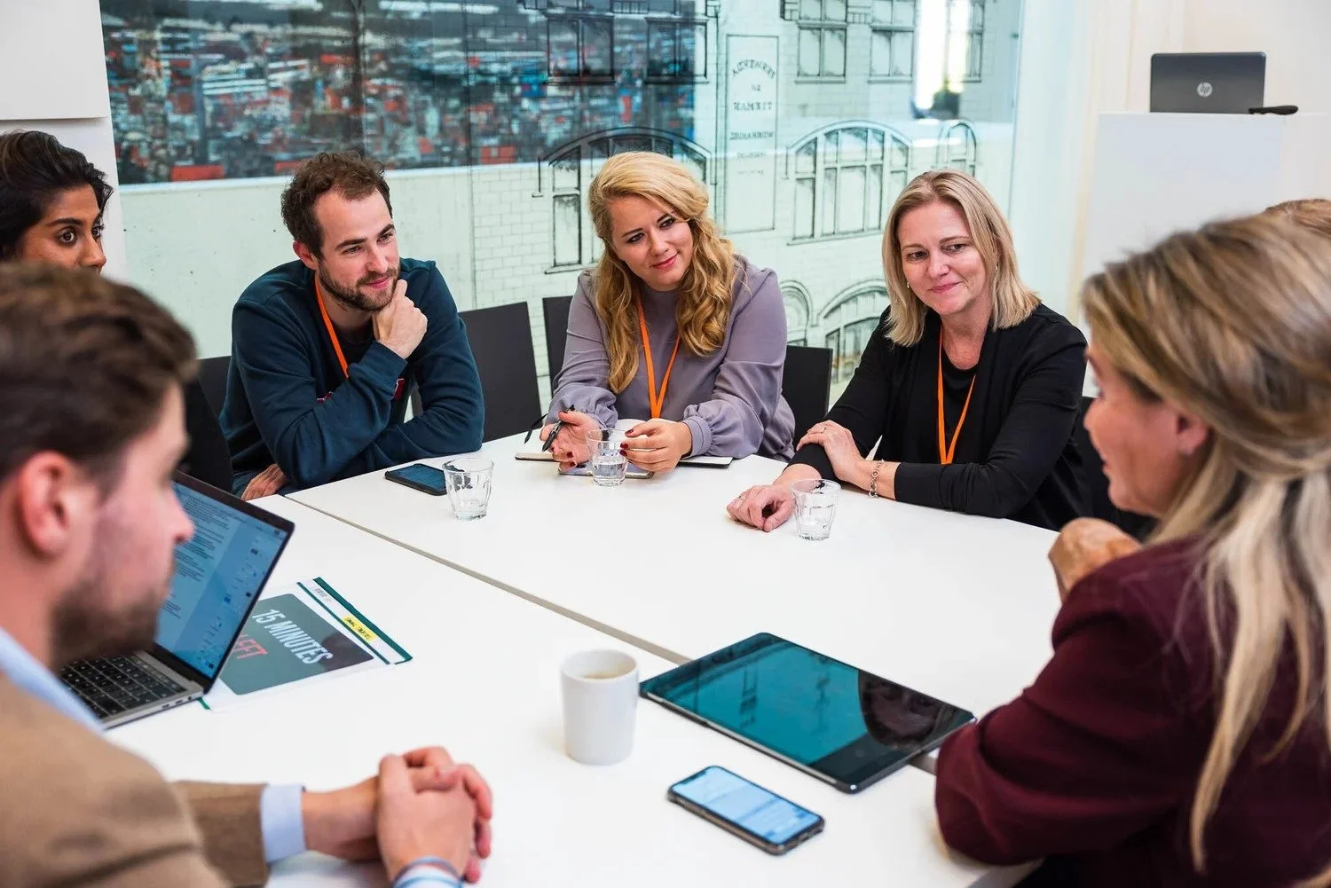 Corporate team meeting around conference table with laptops and tablets during business event Amsterdam — corporate event photography Amsterdam Ballo Studio