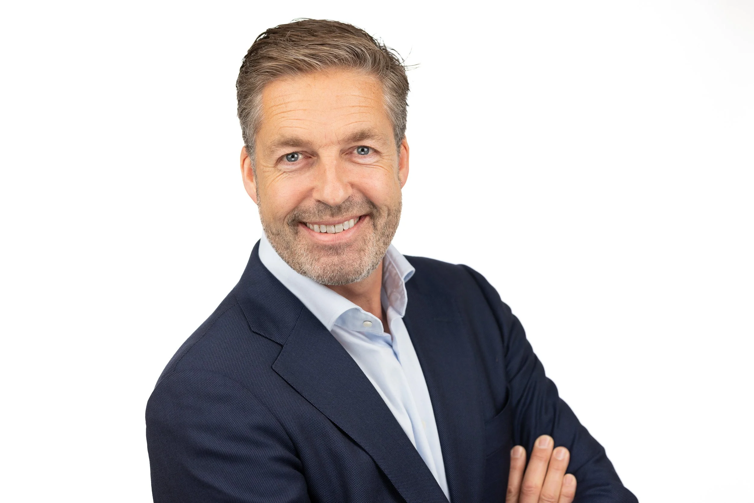 TCI Biotech employee headshot, senior man in navy suit with warm smile, arms crossed — business portrait photography Amsterdam Ballo Studio