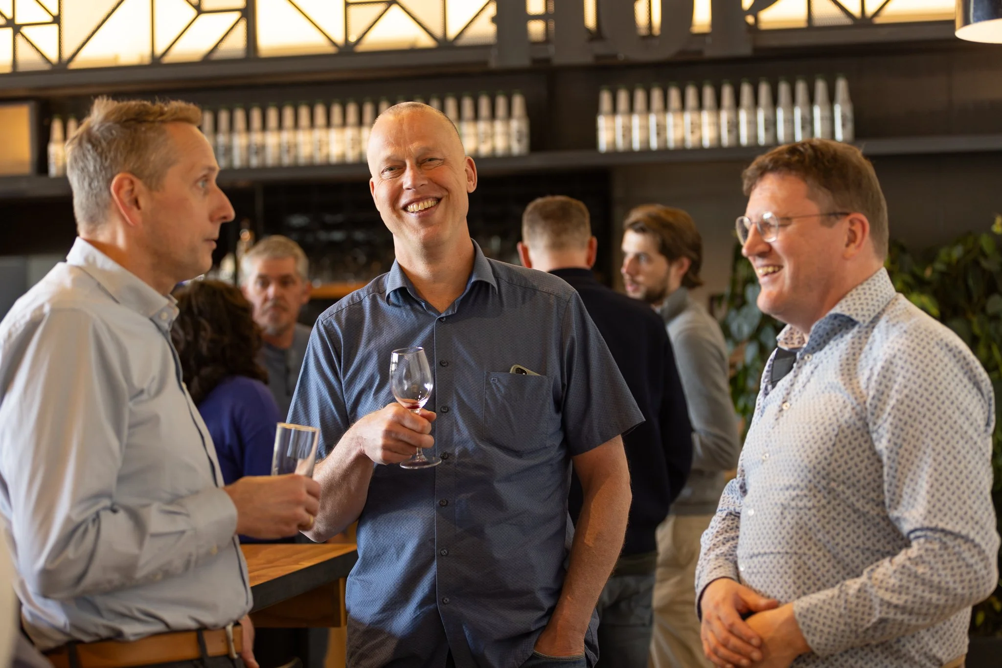 Three Rabobank colleagues laughing during networking drinks at QBR reception — internal event photography Amsterdam Ballo Studio