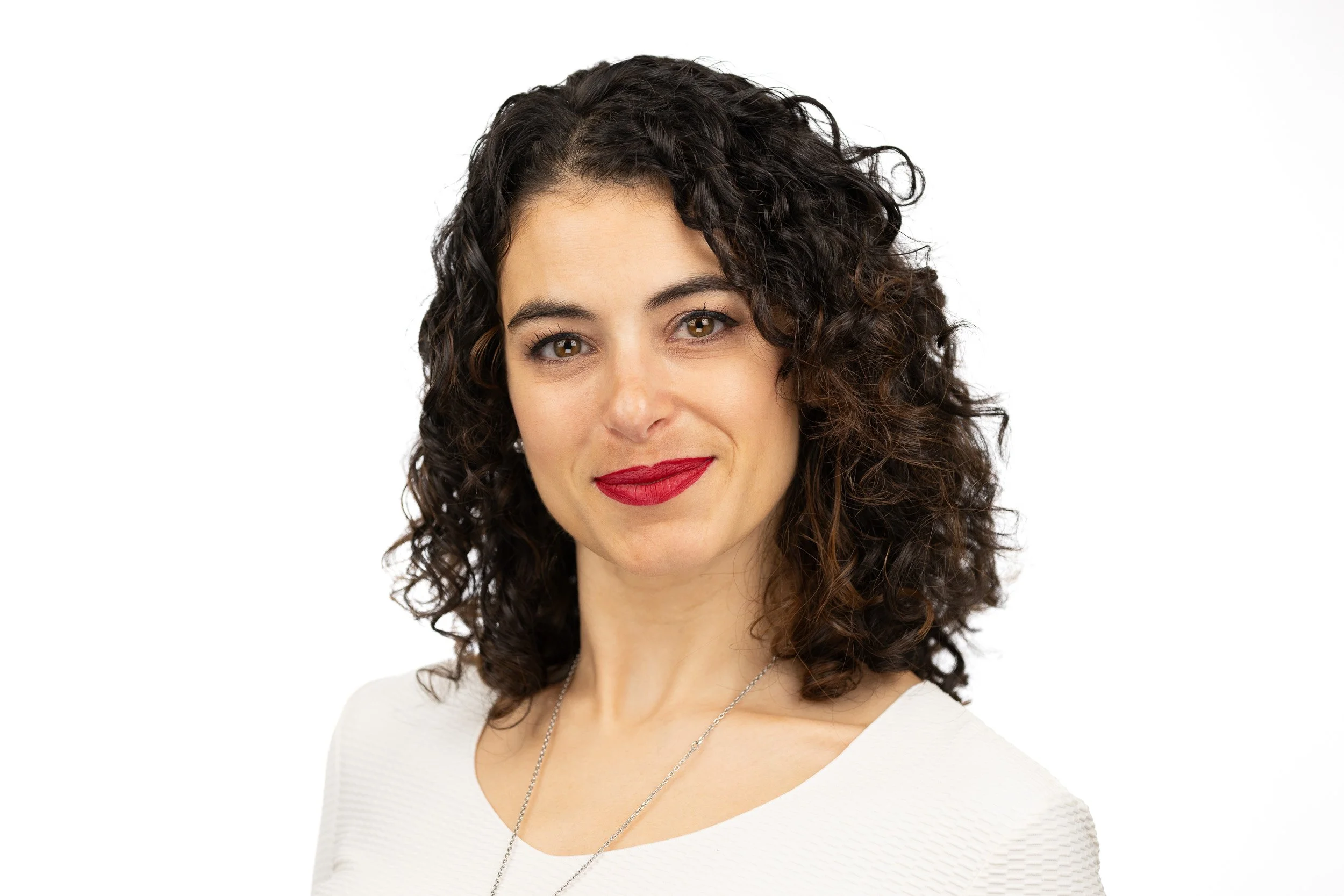 TCI Biotech employee headshot, woman with curly dark hair and red lipstick in white top — on-site headshot studio Amsterdam Ballo Studio