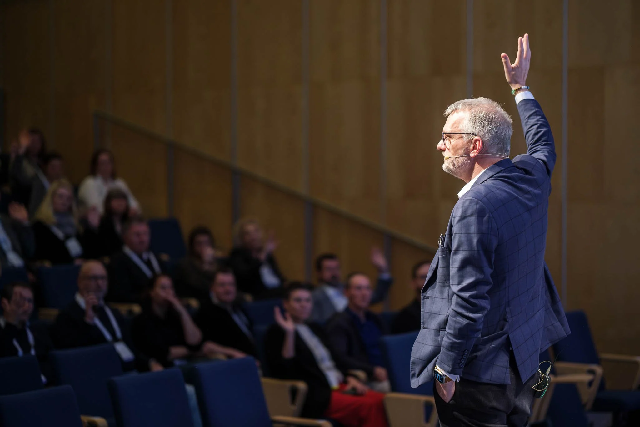 Speaker engaging full auditorium with raised hand at Illuminate EMEA 2026 — Copenhagen event photographer Ballo Studio