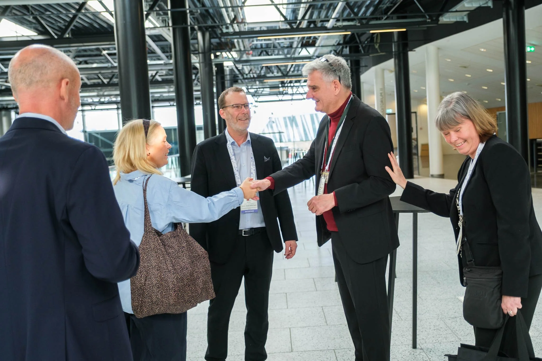 Attendees greeting with handshake at venue entrance at Illuminate EMEA 2026 — Copenhagen conference photographer Ballo Studio