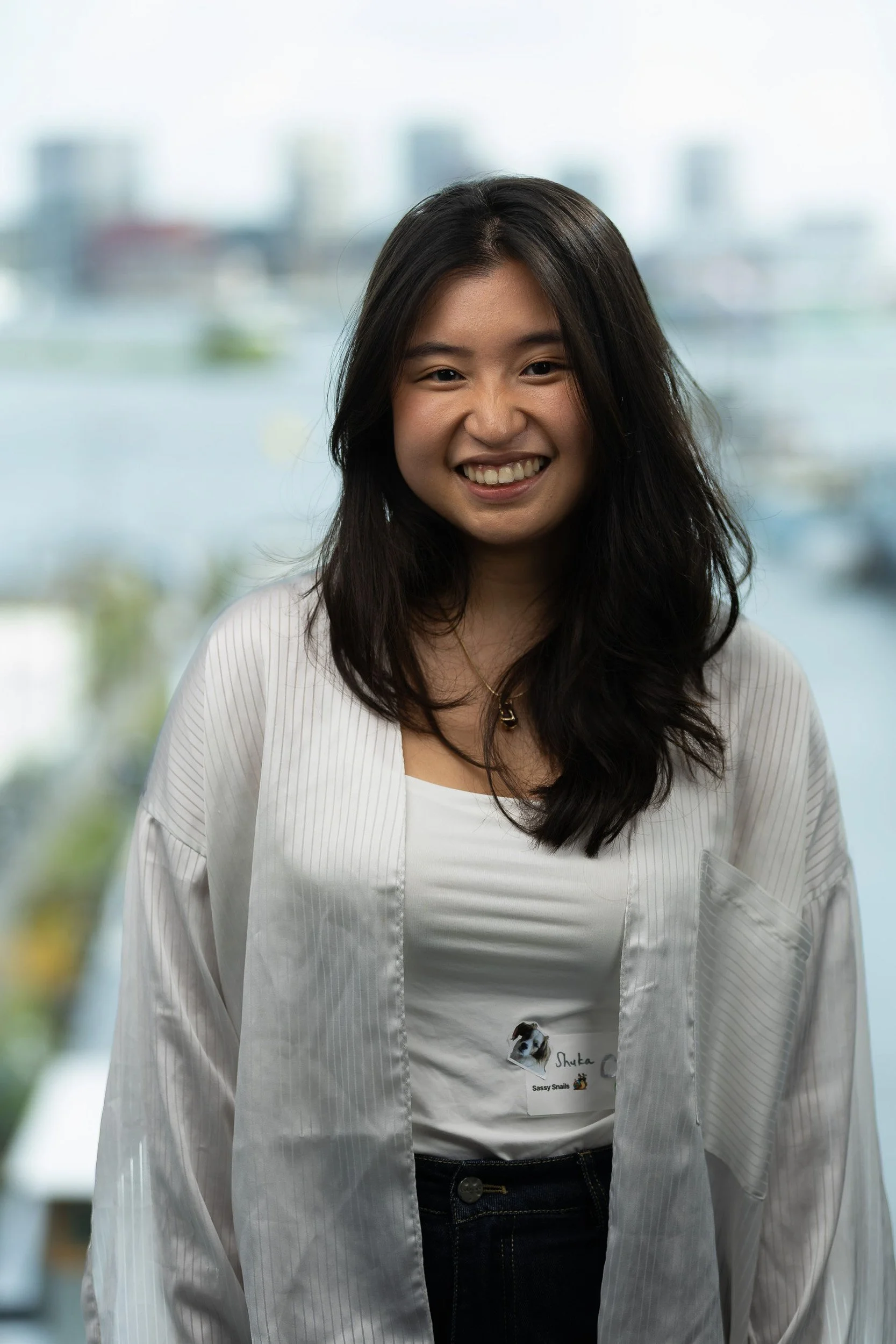 Cheerful female employee portrait in white jacket with Amsterdam skyline and waterfront background — business portrait photography Amsterdam Ballo Studio