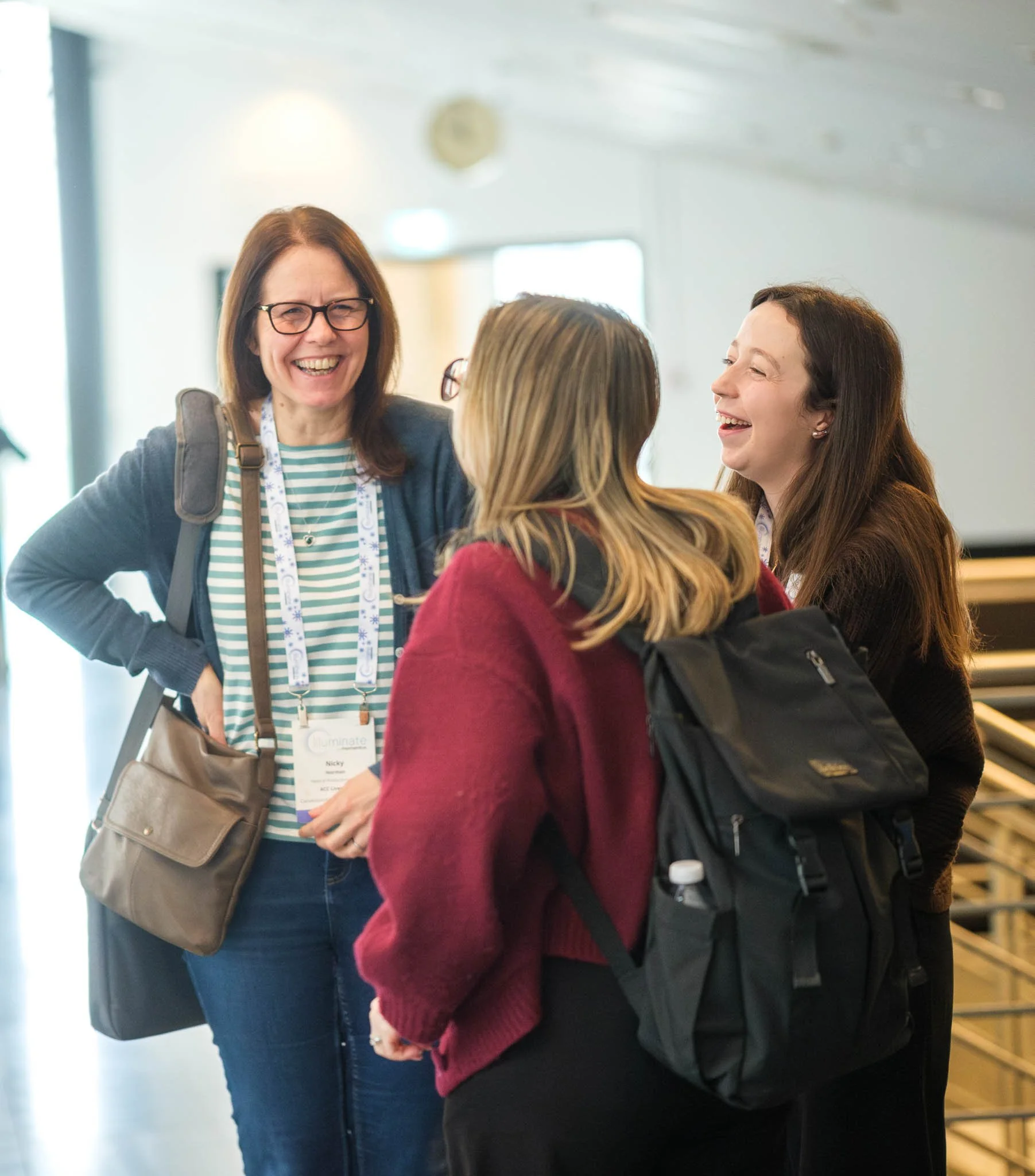 Three delegates laughing during networking break at Illuminate EMEA 2026 — Copenhagen conference photographer Ballo Studio