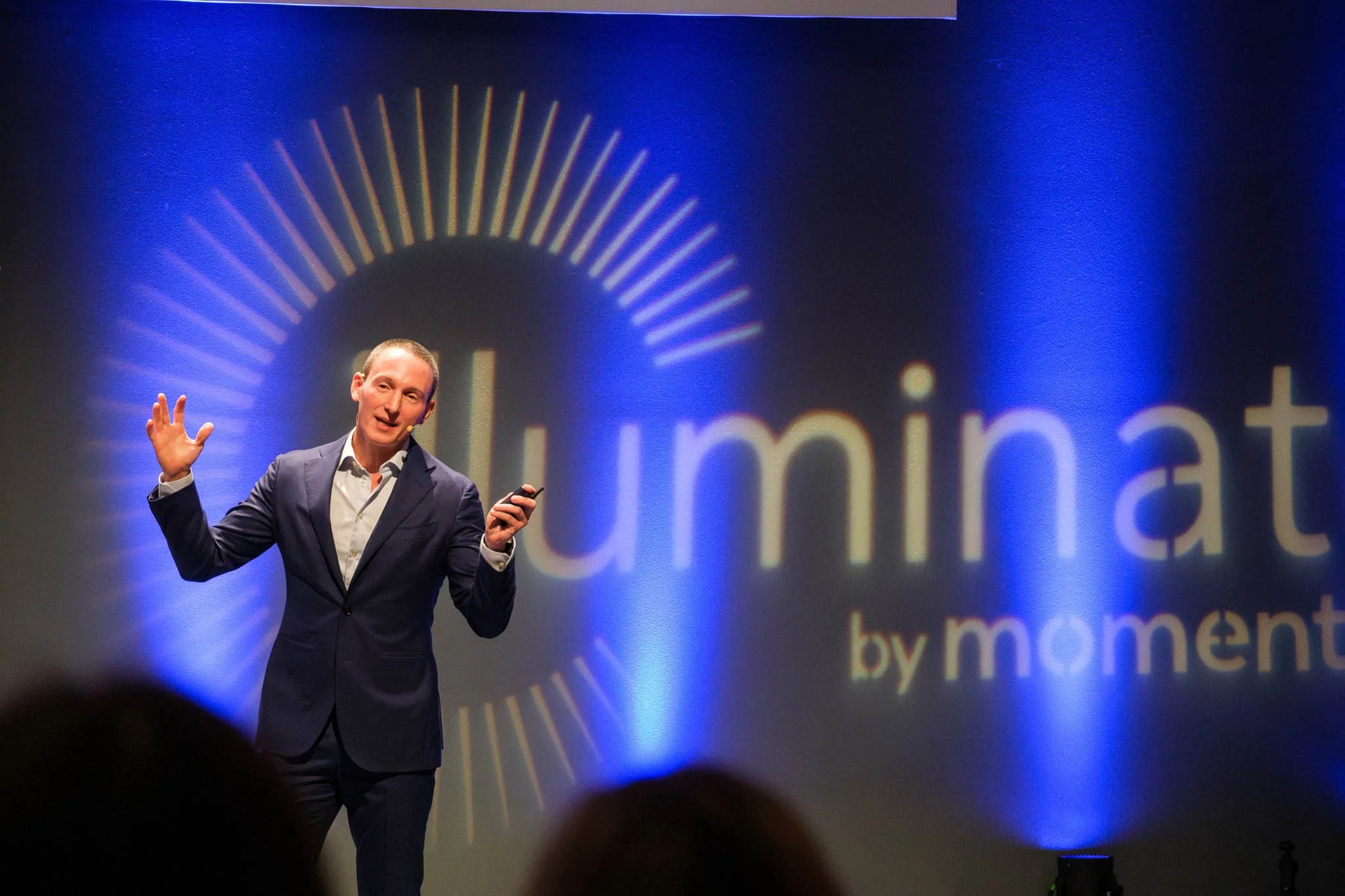 Keynote speaker on stage with open hands at Illuminate EMEA 2026 — Copenhagen corporate conference photography Ballo Studio
