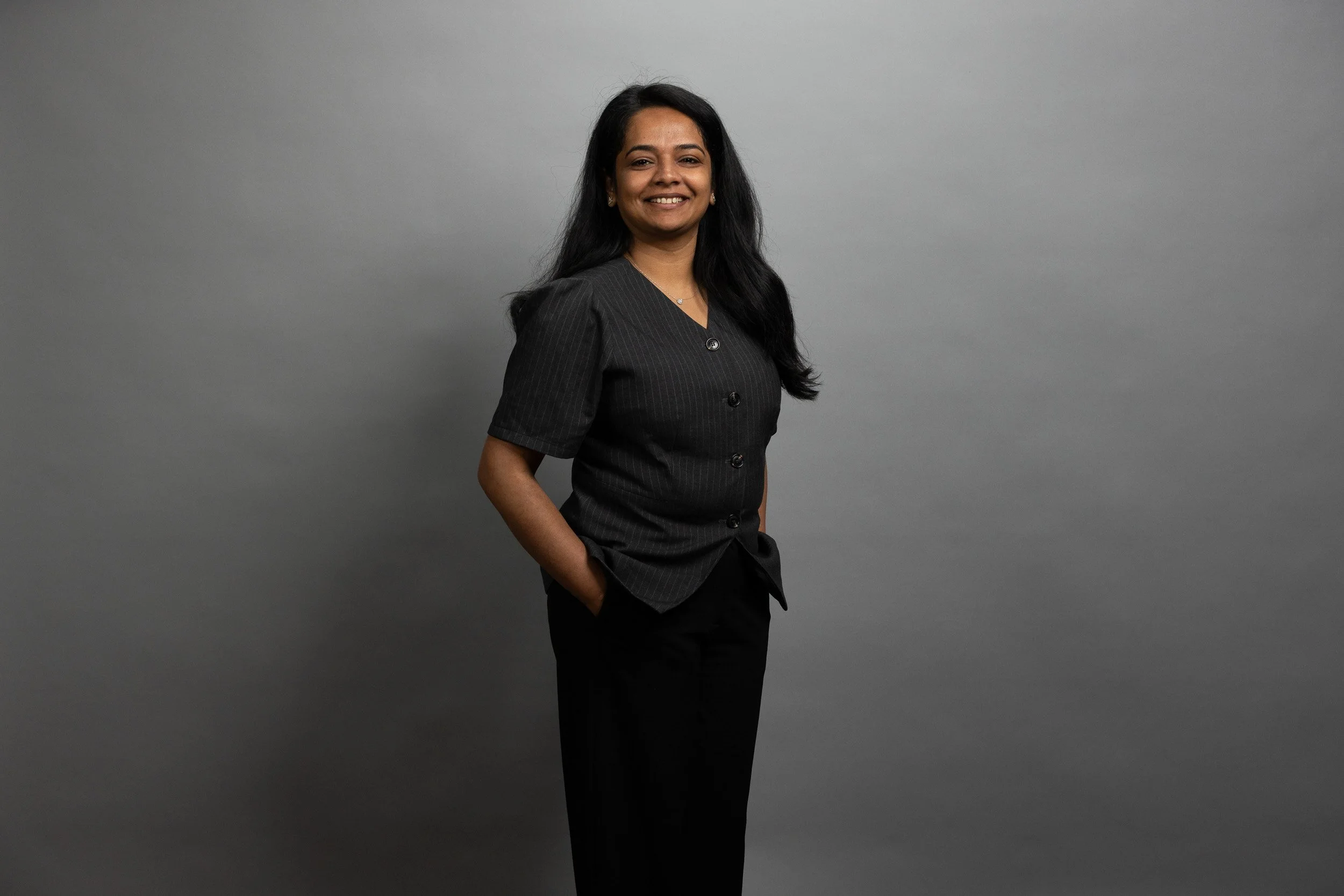 EPEX SPOT employee portrait, smiling woman with long dark hair in dark grey top — employee headshots Amsterdam Ballo Studio