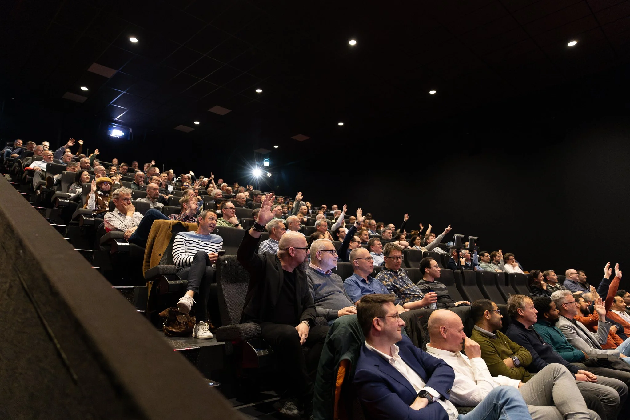 Rabobank QBR audience raising hands during interactive session in packed Kinepolis cinema — corporate event photography Amsterdam Ballo Studio
