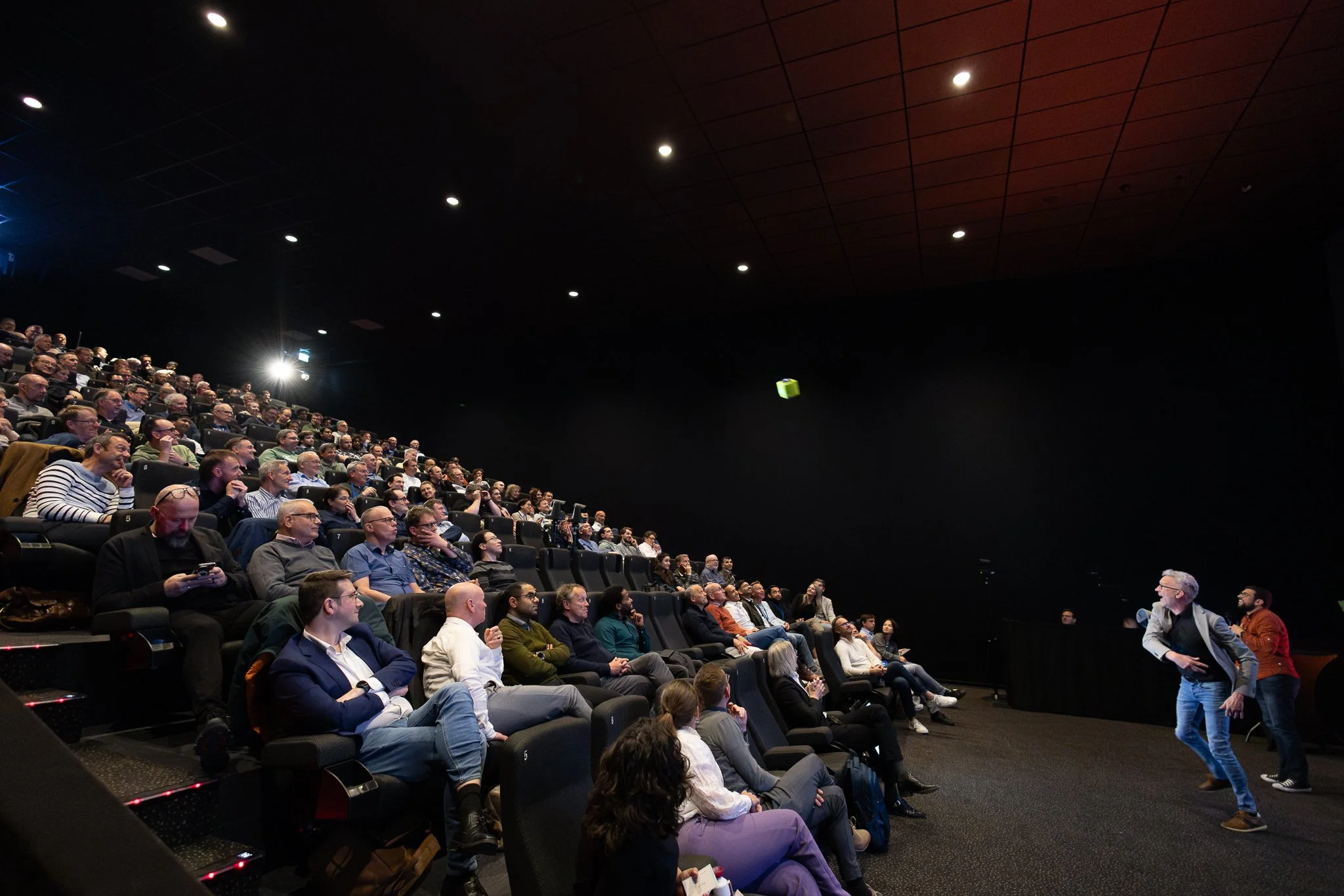 Rabobank presenter holding green gift box during QBR award moment in Kinepolis cinema auditorium — event photography Amsterdam Ballo Studio