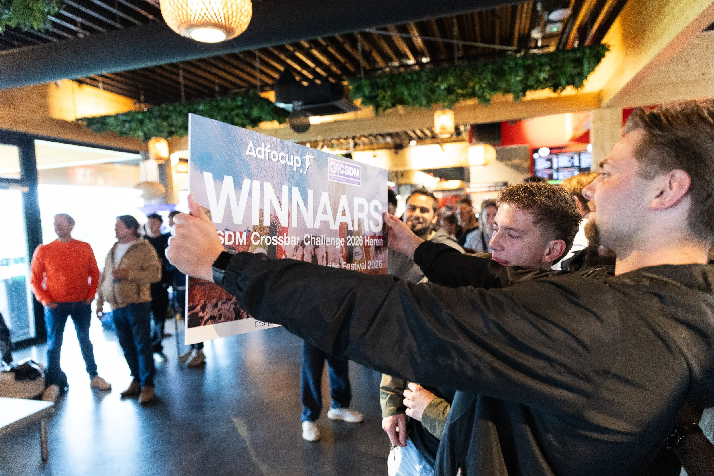 Two winners holding up CSDM Crossbar Challenge 2026 winners banner at Adfocup prize ceremony Amsterdam — corporate event photography Amsterdam Ballo Studio