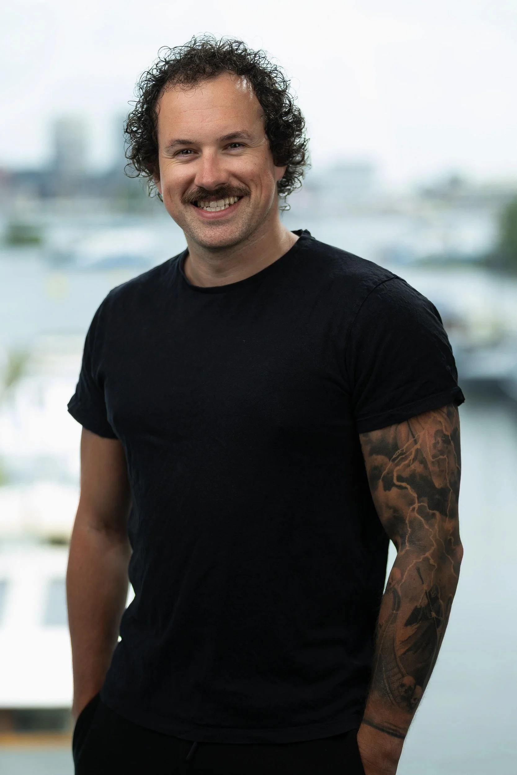 Smiling male employee headshot in black t-shirt with Amsterdam canal background — employee headshots Amsterdam Ballo Studio