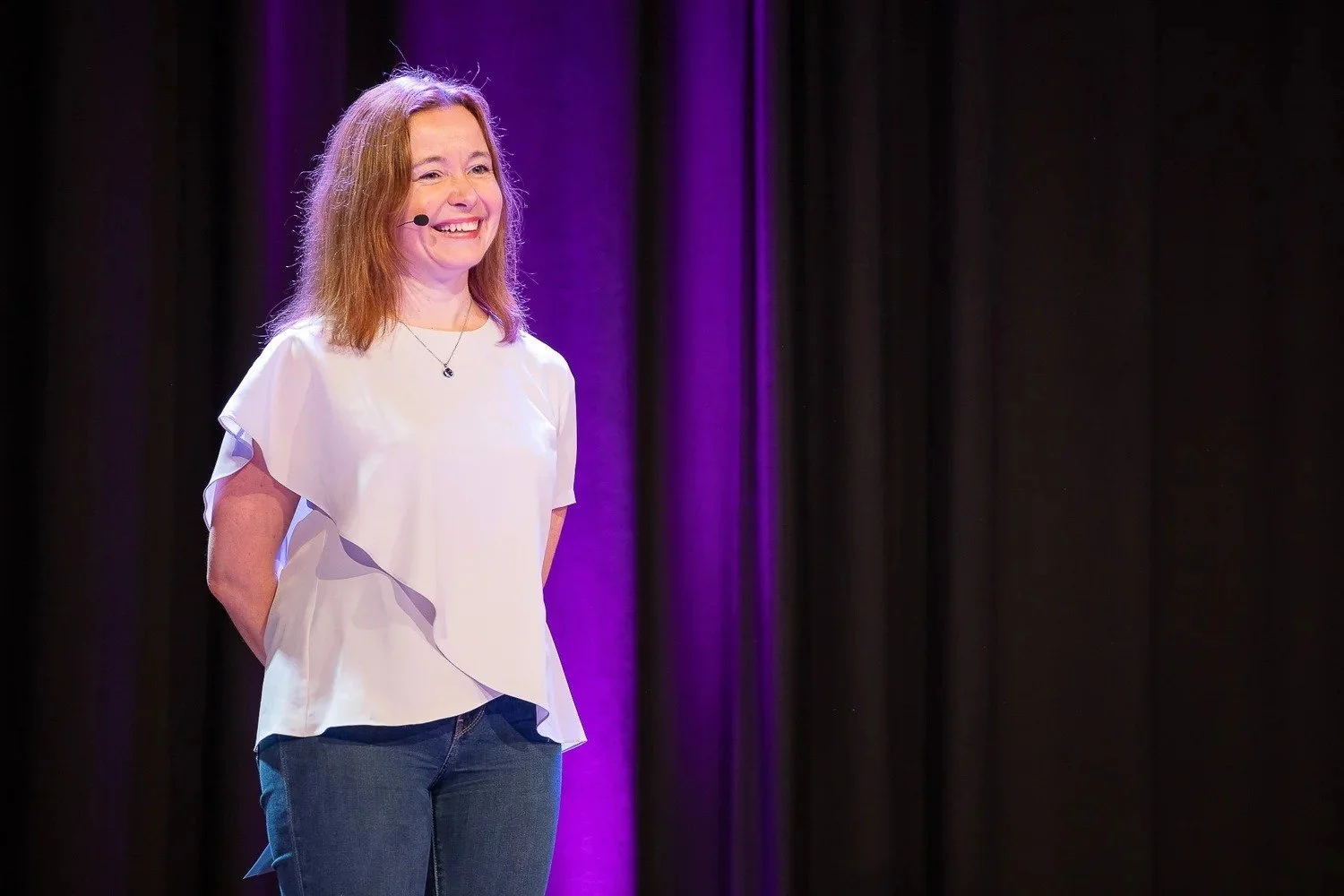 Speaker smiling on stage with purple event lighting at corporate conference Amsterdam — conference photography Amsterdam Ballo Studio