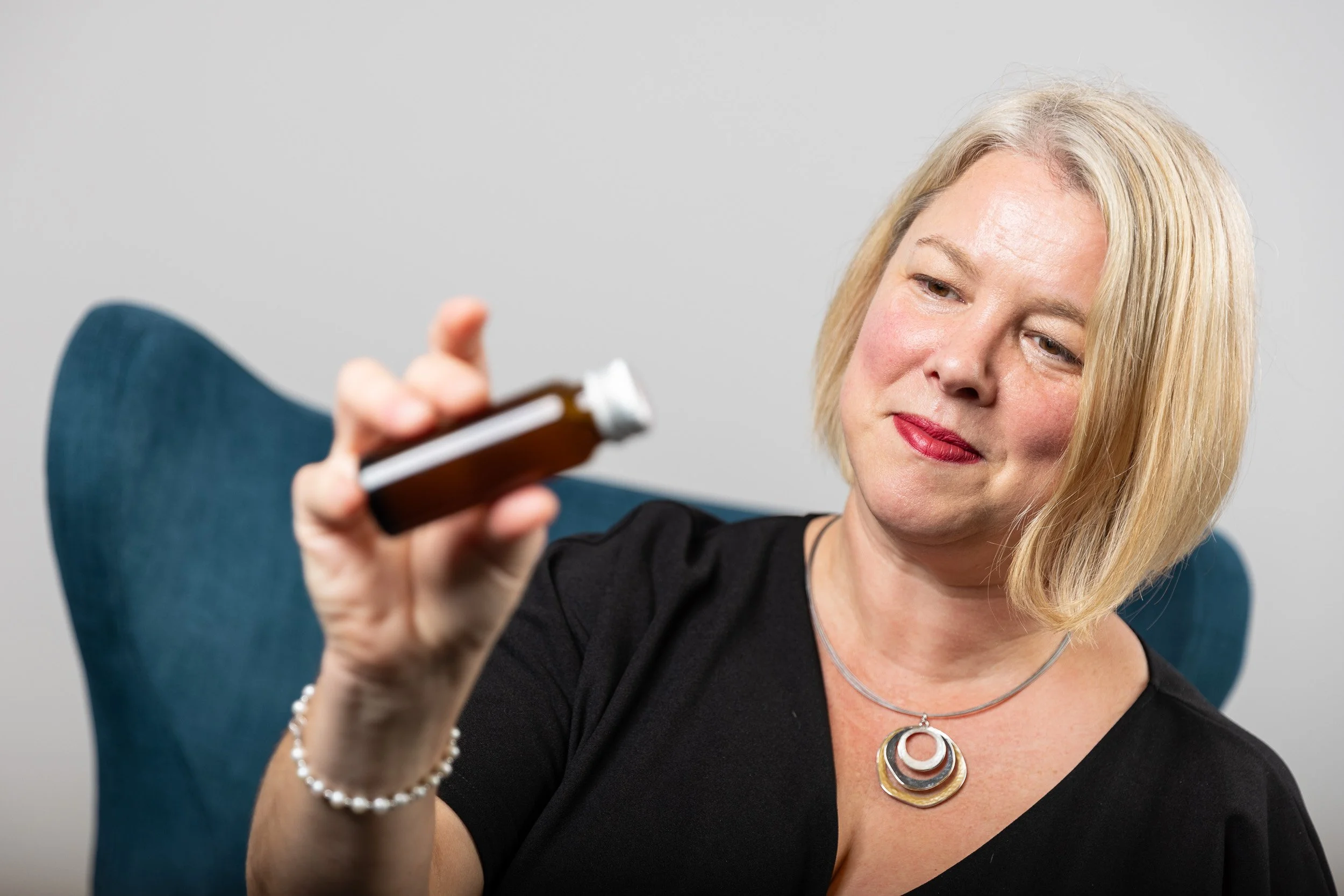 TCI Biotech employee portrait, blonde woman holding pharmaceutical vial, seated editorial pose — on-site headshot studio Amsterdam Ballo Studio