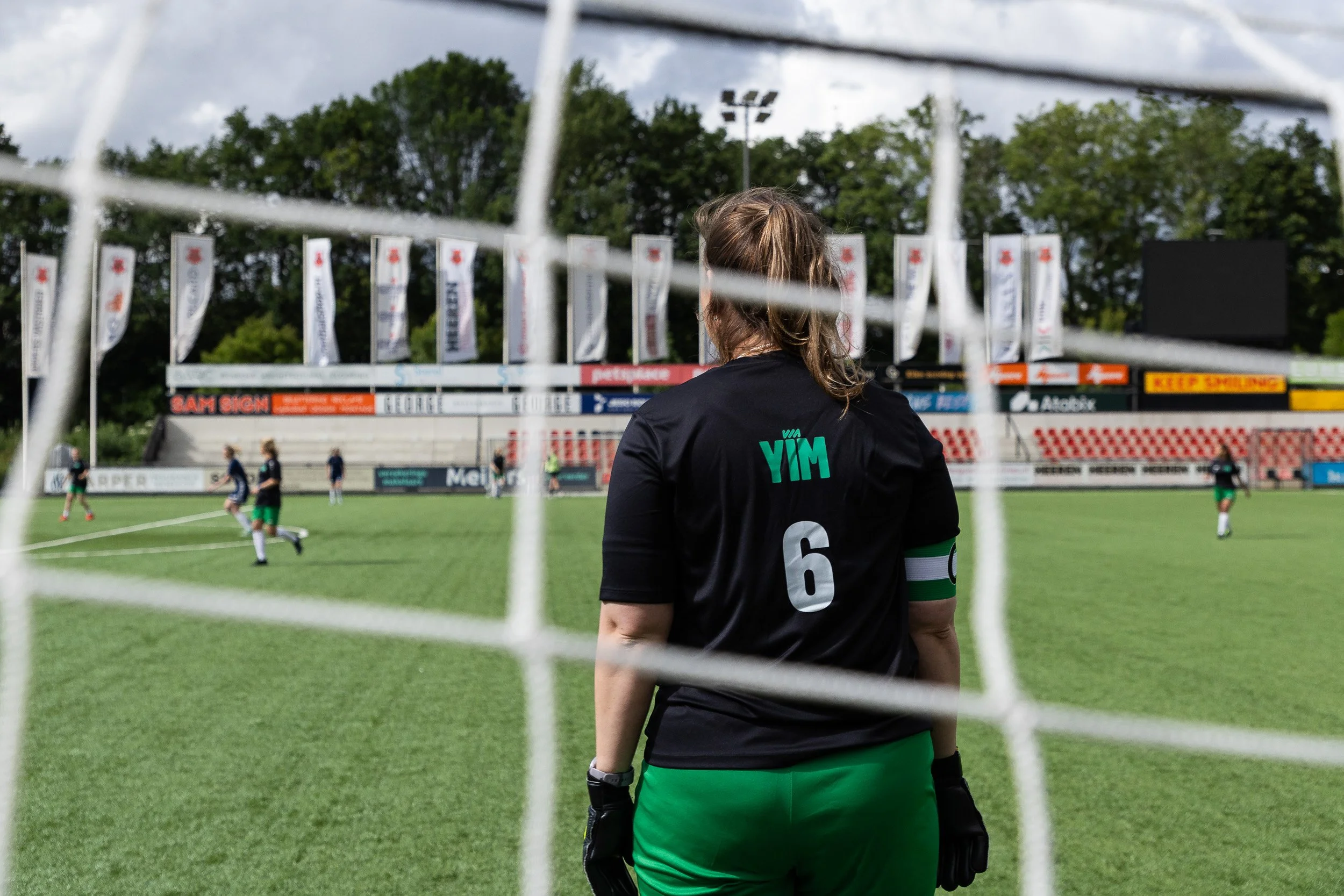 Goalkeeper in YIM kit seen through goal net during Adfocup 2026 advertising industry football match Amsterdam — event photographer Amsterdam Ballo Studio