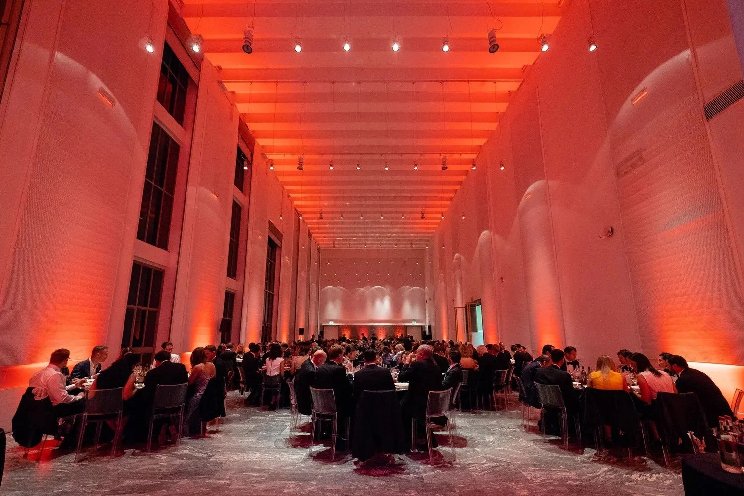 Gala dinner in dramatic red-lit hall with guests at round tables at corporate awards event Amsterdam — gala dinner photography Amsterdam Ballo Studio