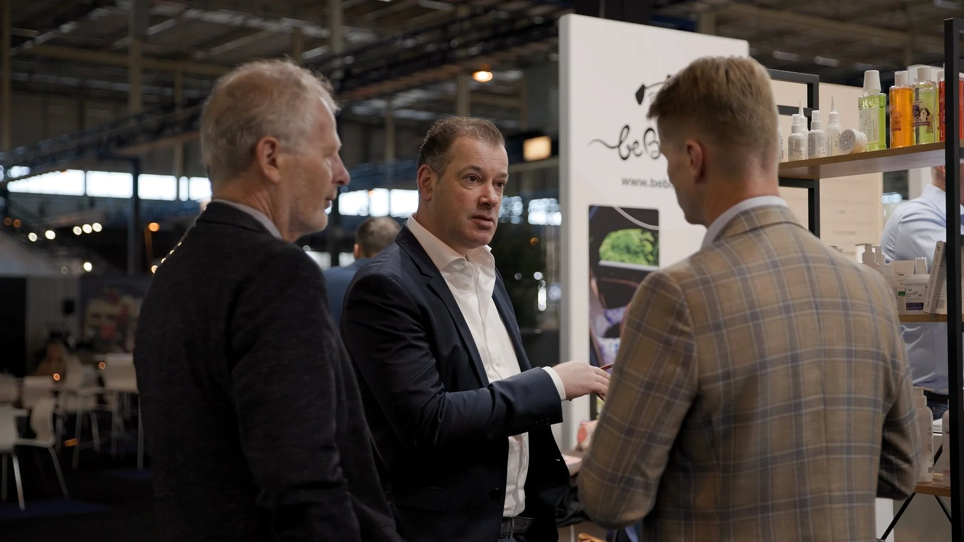 Business discussion between delegates at Polish cosmetics exhibitor stand during PAIH trade mission — conference photography Amsterdam Ballo Studio