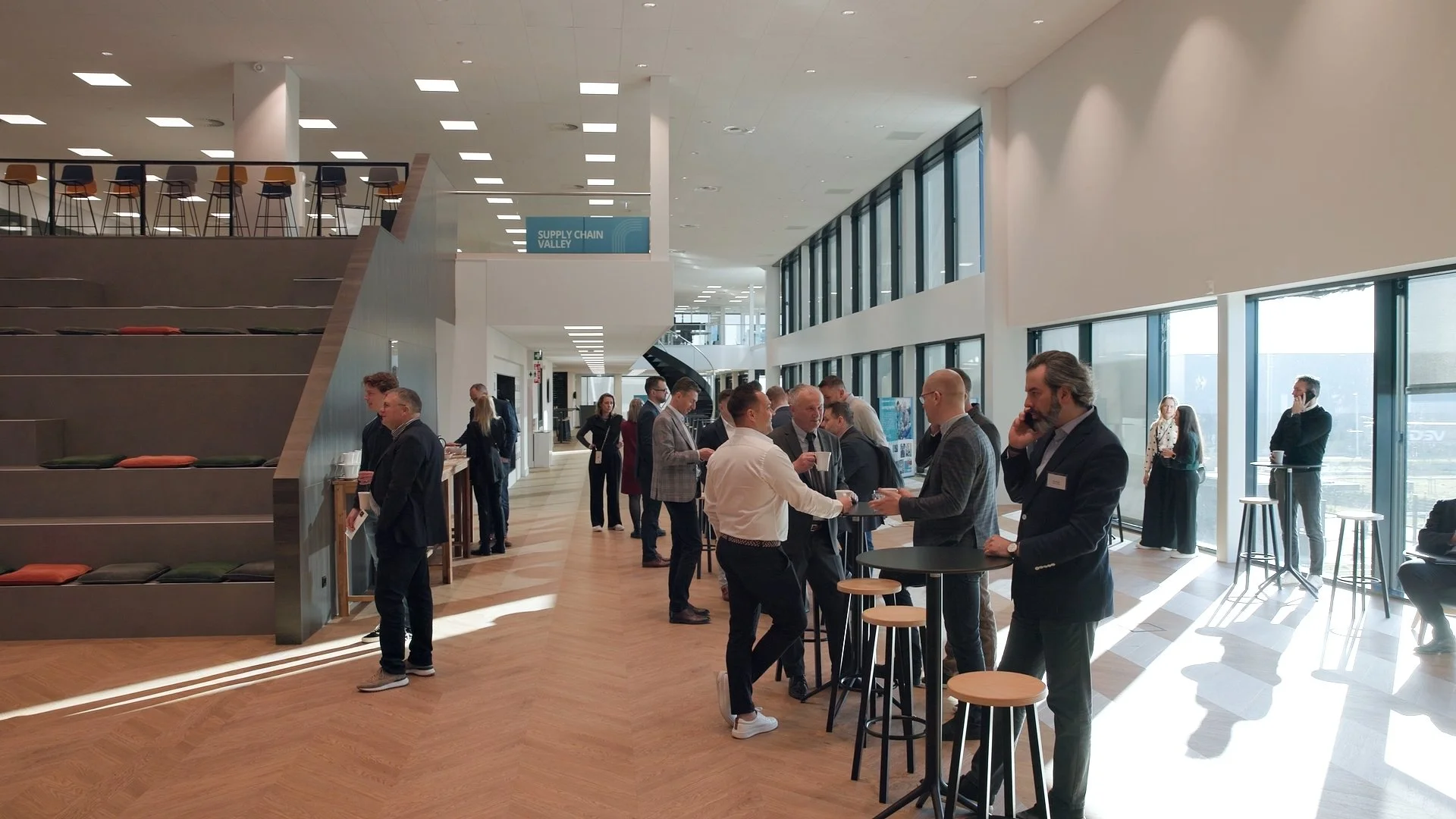 Business delegates networking at reception during PAIH Polish-Dutch Economic Mission in modern waterfront venue — event photographer Amsterdam Ballo Studio