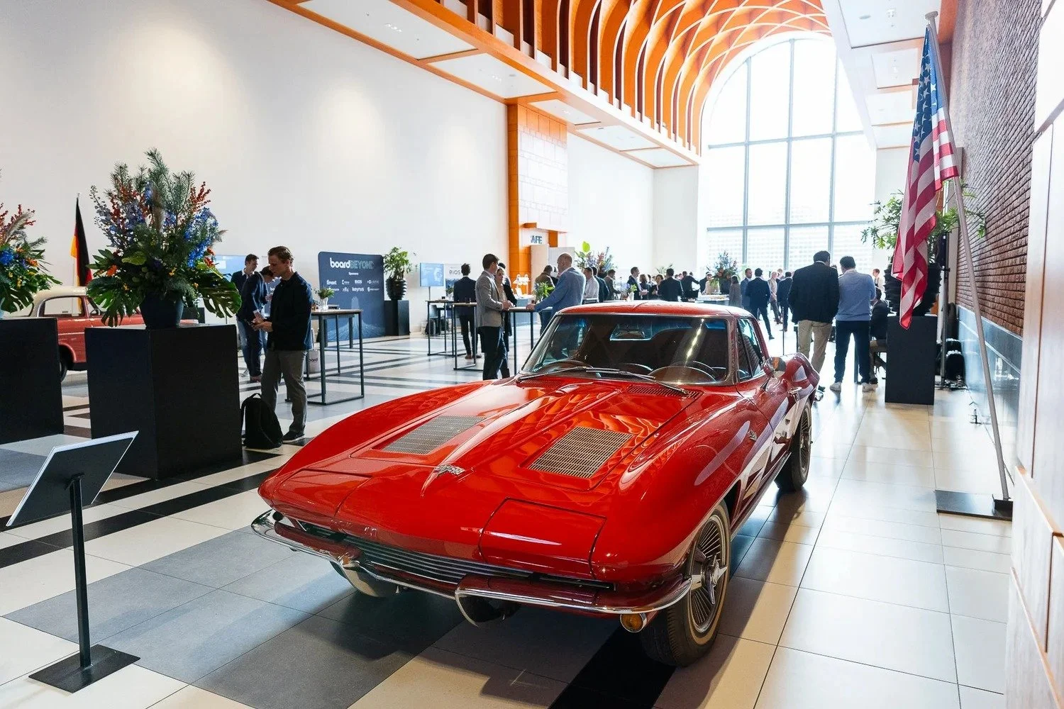 Classic red Corvette on display in modern event venue foyer with attendees at corporate conference Amsterdam — corporate event photography Amsterdam Ballo Studio