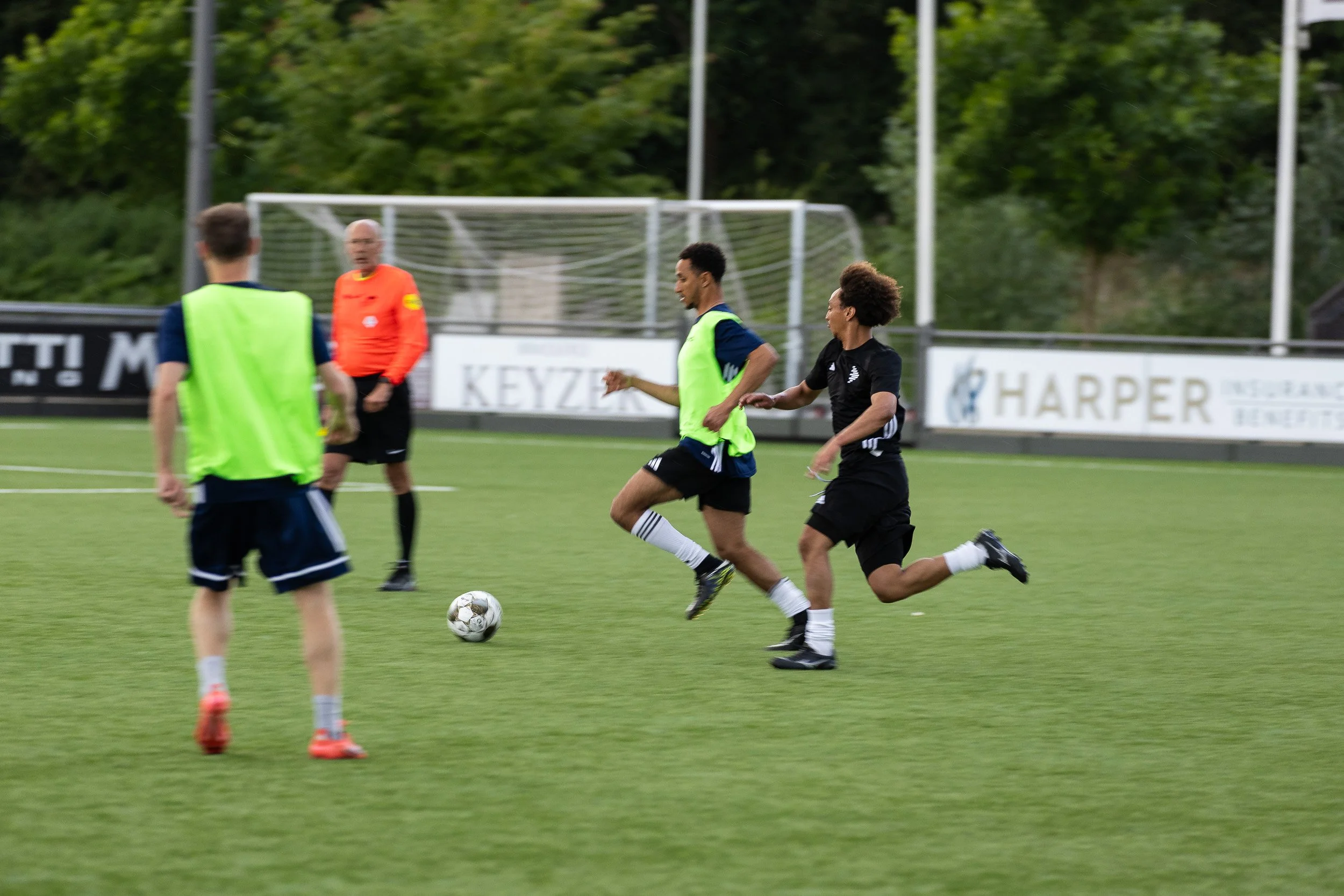 Players competing for the ball with referee watching during Adfocup 2026 advertising industry football match Amsterdam — corporate event photography Amsterdam Ballo Studio