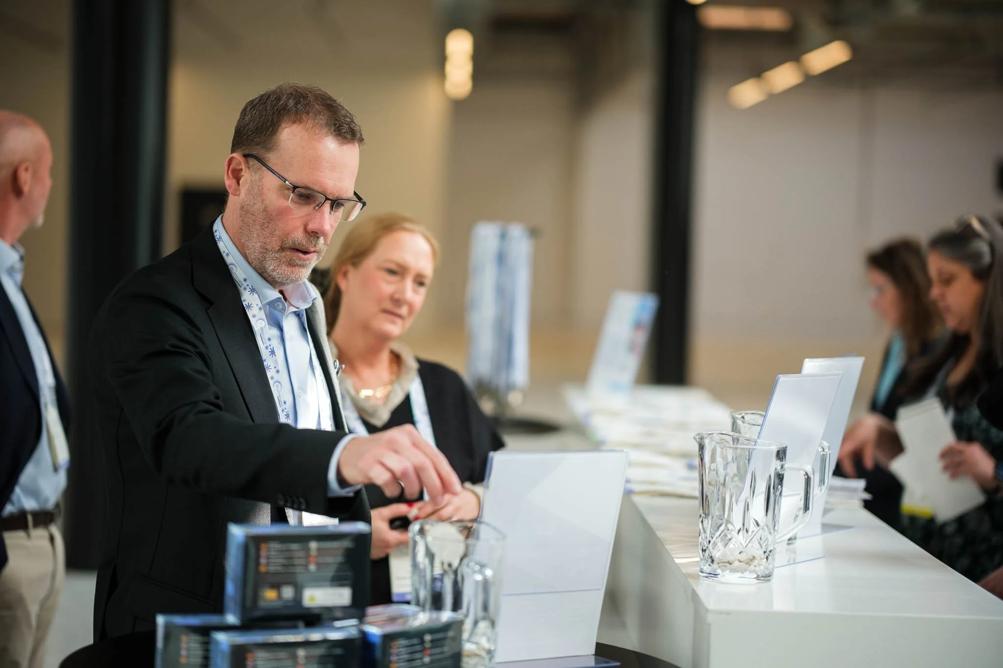 Delegate collecting badge at registration desk at Illuminate EMEA 2026 — Copenhagen conference photography Ballo Studio