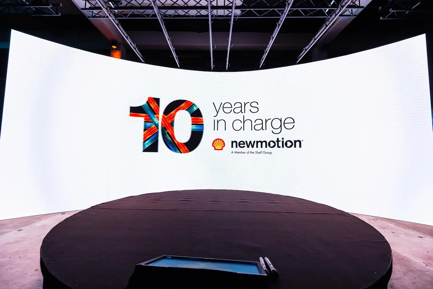 A large digital screen displaying a celebration message for 10 years in charge of Shell's NewMotion, featuring the Shell logo and a colorful number 10.