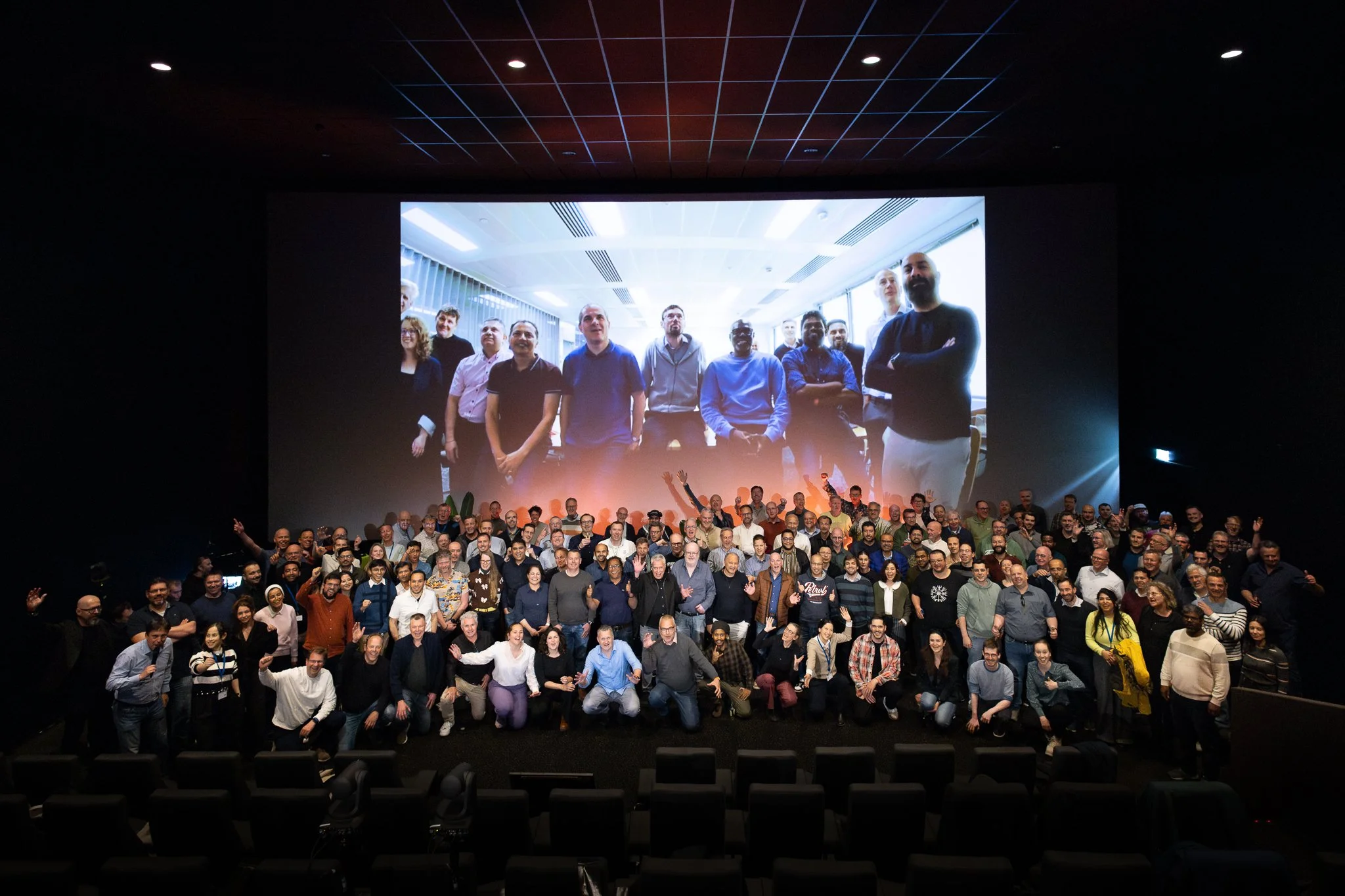 Rabobank QBR keynote in Kinepolis cinema, presenter at front with F1 racing visual on screen — internal event photography Amsterdam Ballo Studio