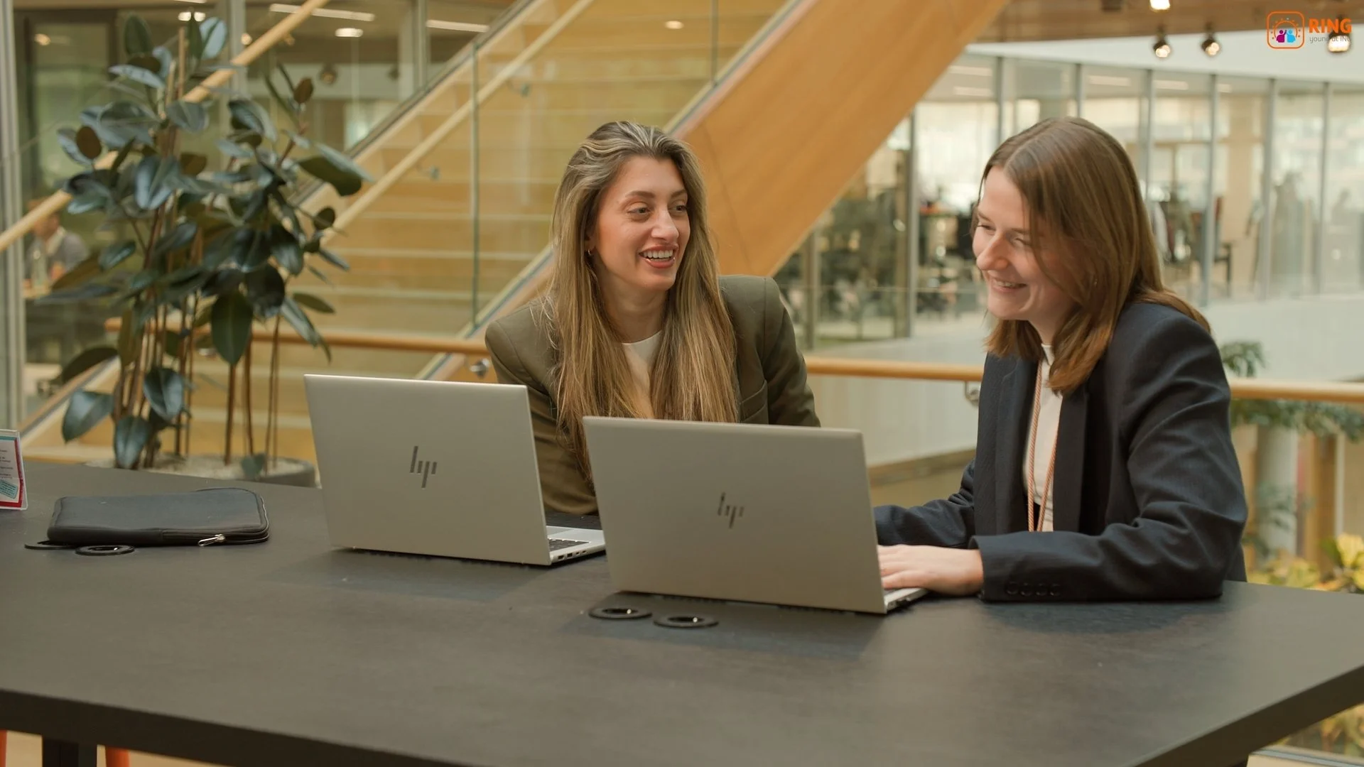 Two ING employees collaborating on laptops in modern Amsterdam office atrium for internal comms video — corporate video production Amsterdam Ballo Studio