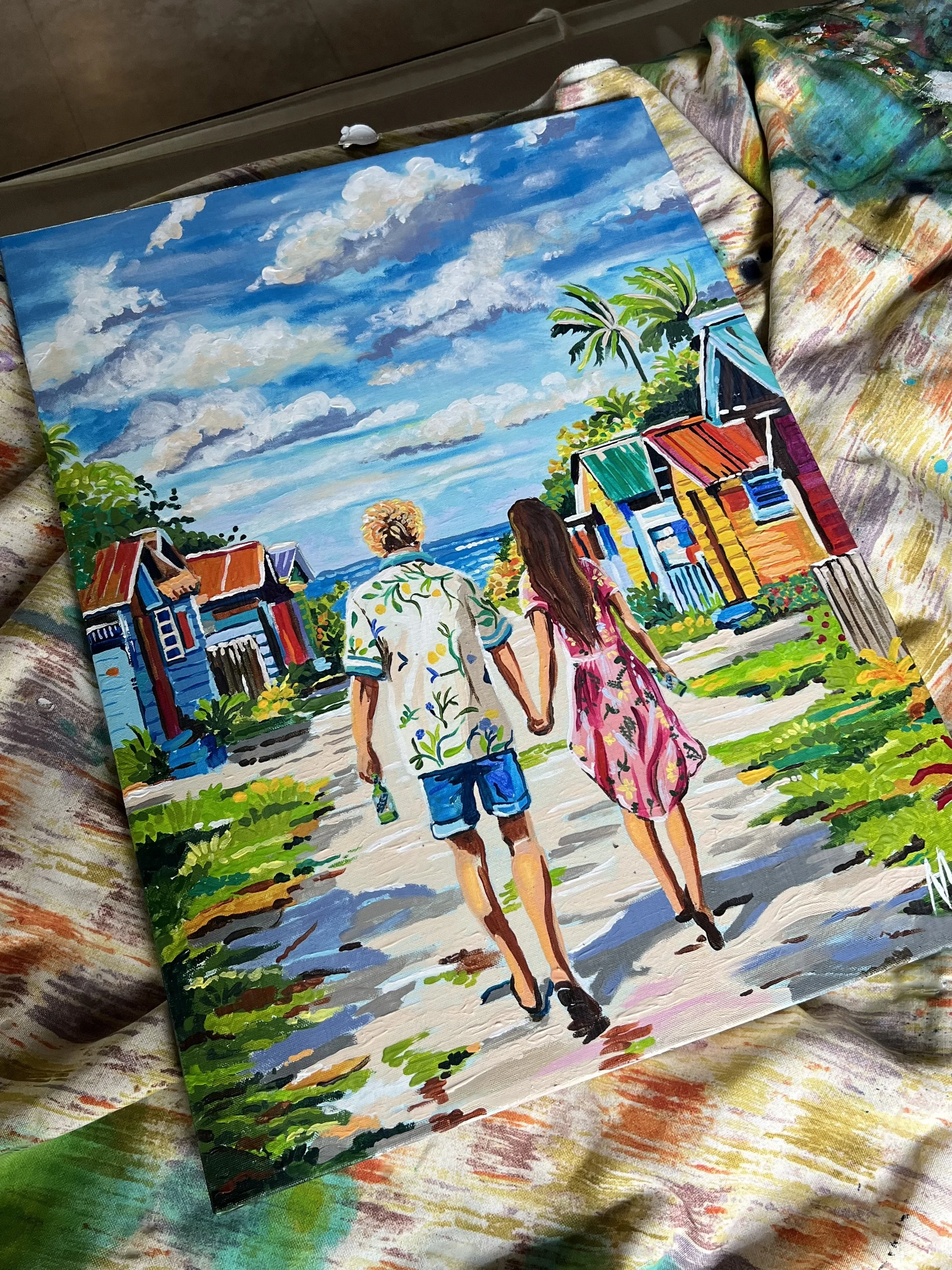 Colorful painting of a couple walking hand in hand along a beachside street, with vibrant houses, lush greenery, and a bright blue sky with clouds.