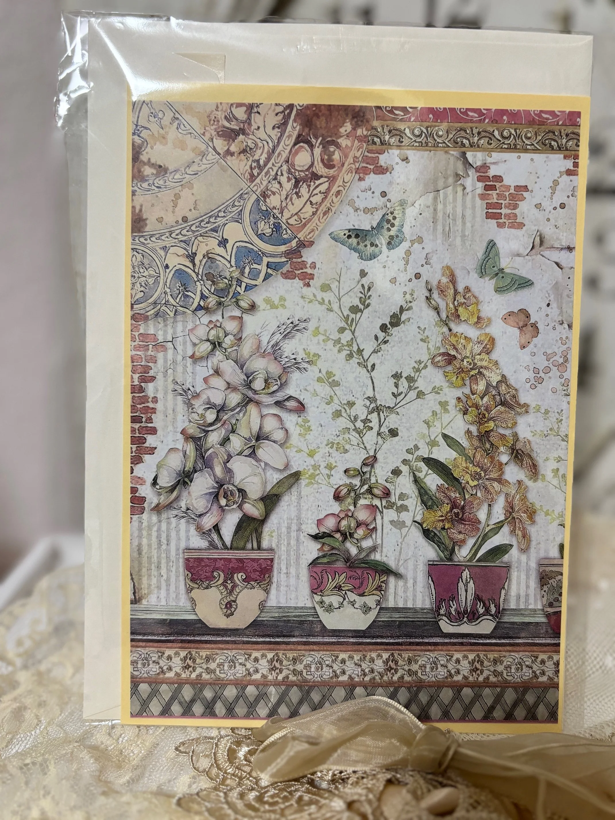 Eine Karte mit einem Blumenarrangement in drei Vasen vor einer dekorativen Wand mit Schmetterlingen und Bienen.