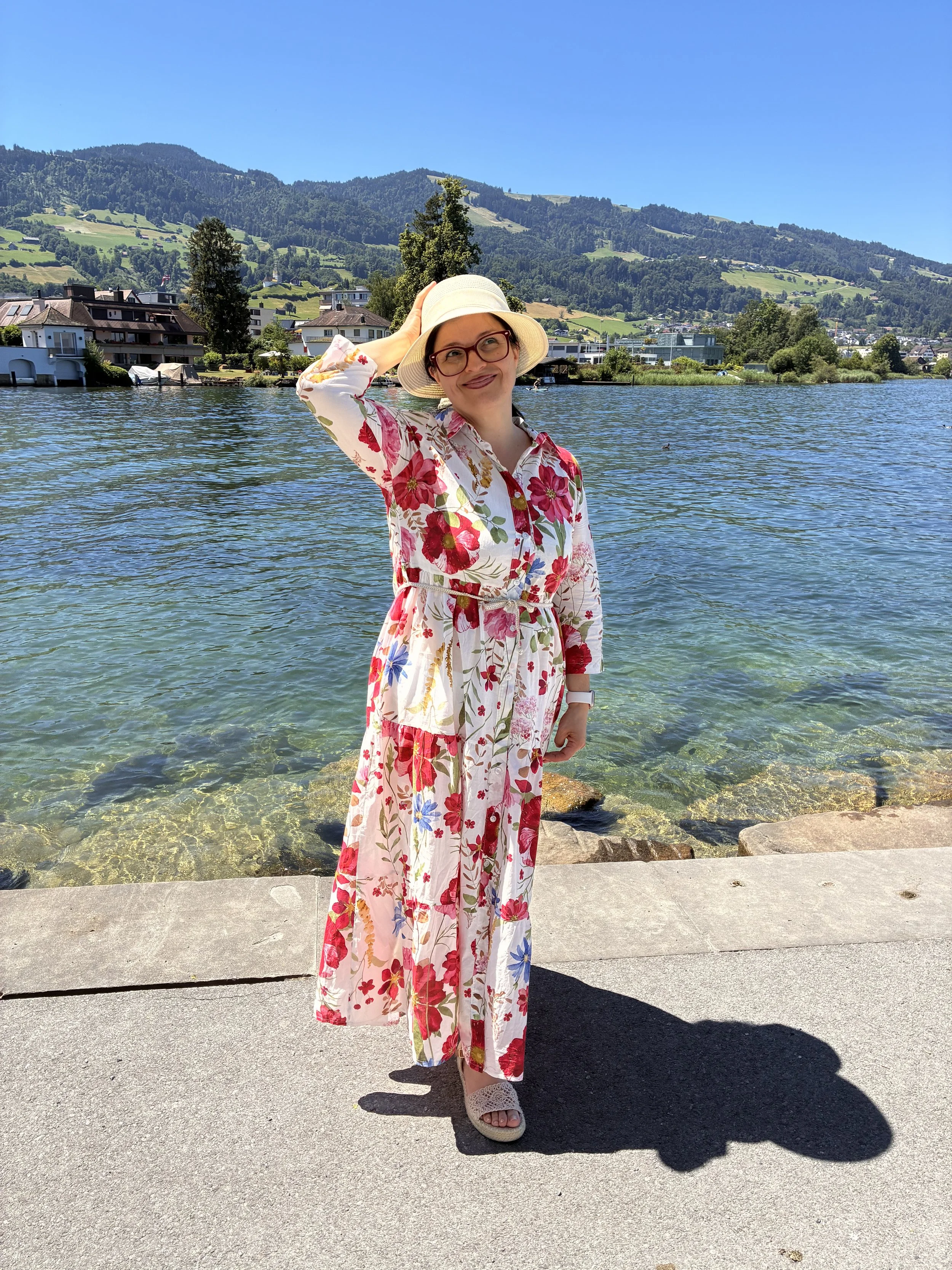 Frau in Sommerkleid und Hut am See